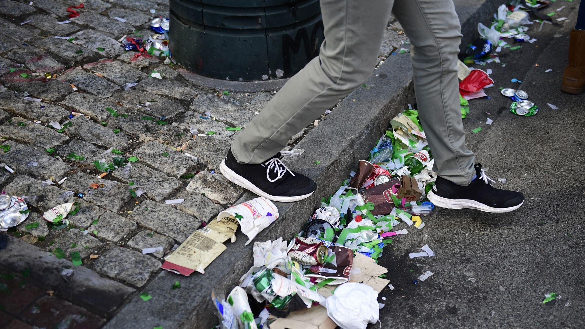 In this image, someone steps over a curb at the super bowl. the curb is covered in trash