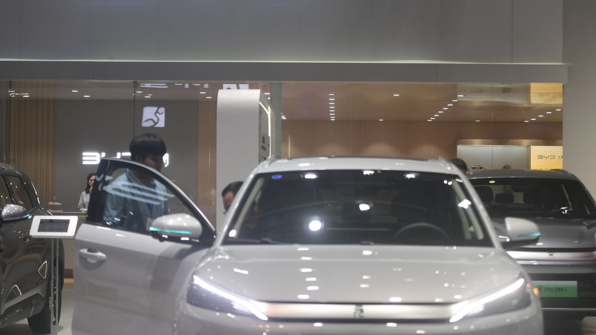 A shimmering silver vehicle below a BYD sign