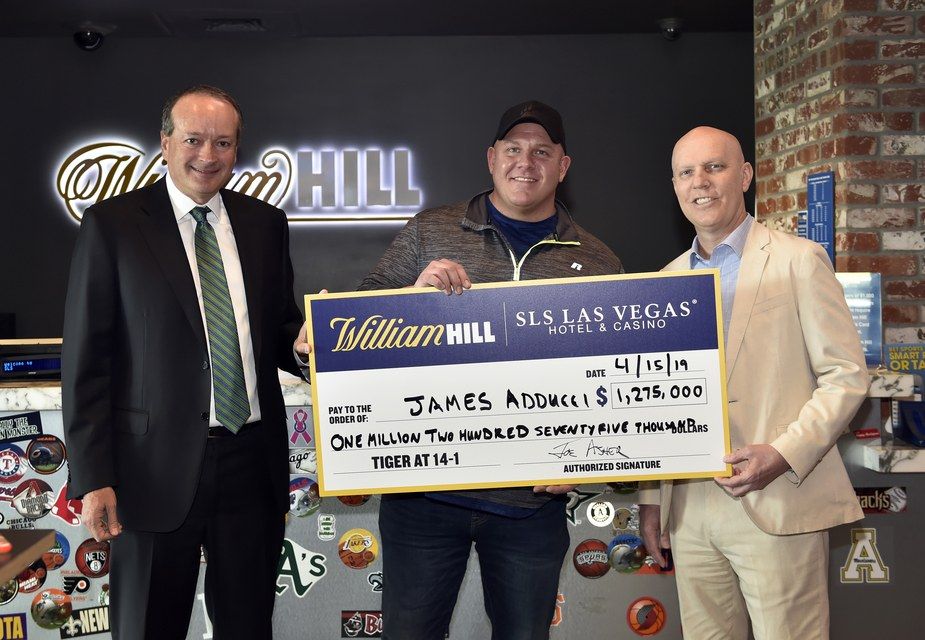 William Hill US CEO Joe Asher (left), James Adducci and SLS Las Vegas general manager Paul Hobson (right) stand with a ceremonial check of Adducci's winnings.