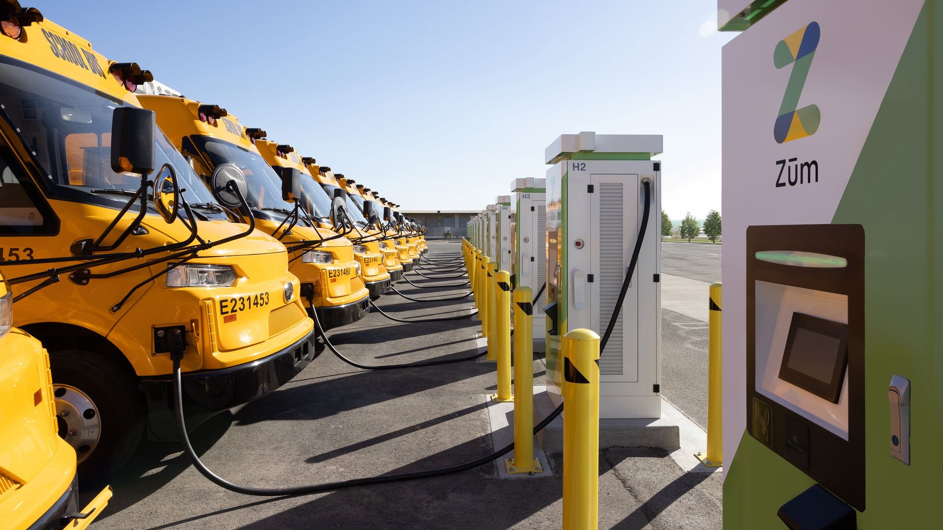 A row of electric school buses plugged into chargers that can send electricity back to the grid in Oakland, Calif.