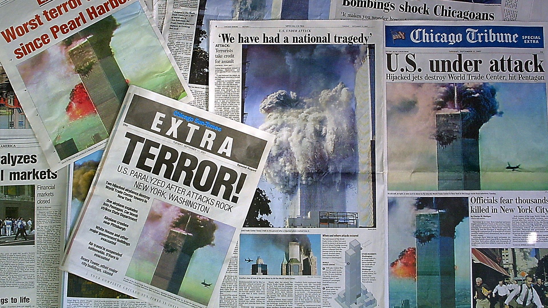 Collage of newspaper front pages about 9/11, with bold headlines like "Worst terror attack since Pearl Harbor" and "U.S. under attack," smoke rising from the towers, and crowds.