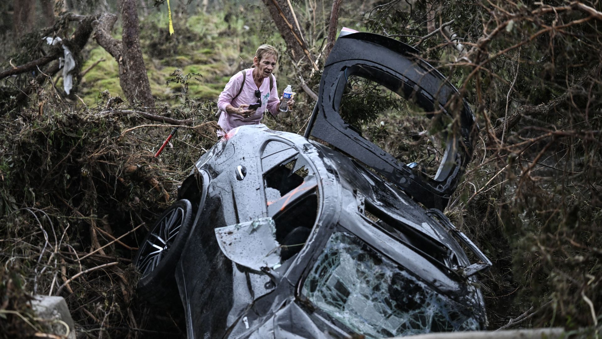 A volunteer in Texas looks at a badly damaged car after catastrophic flooding in Texas.