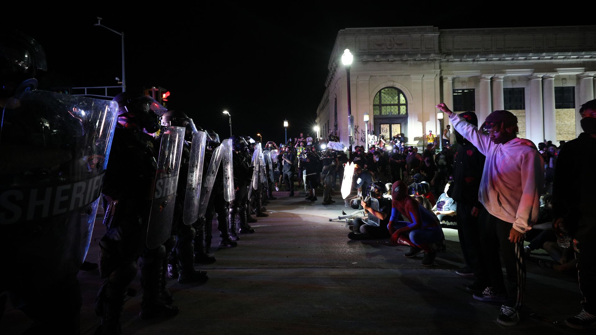 A line of protesters stand across from a line of police 