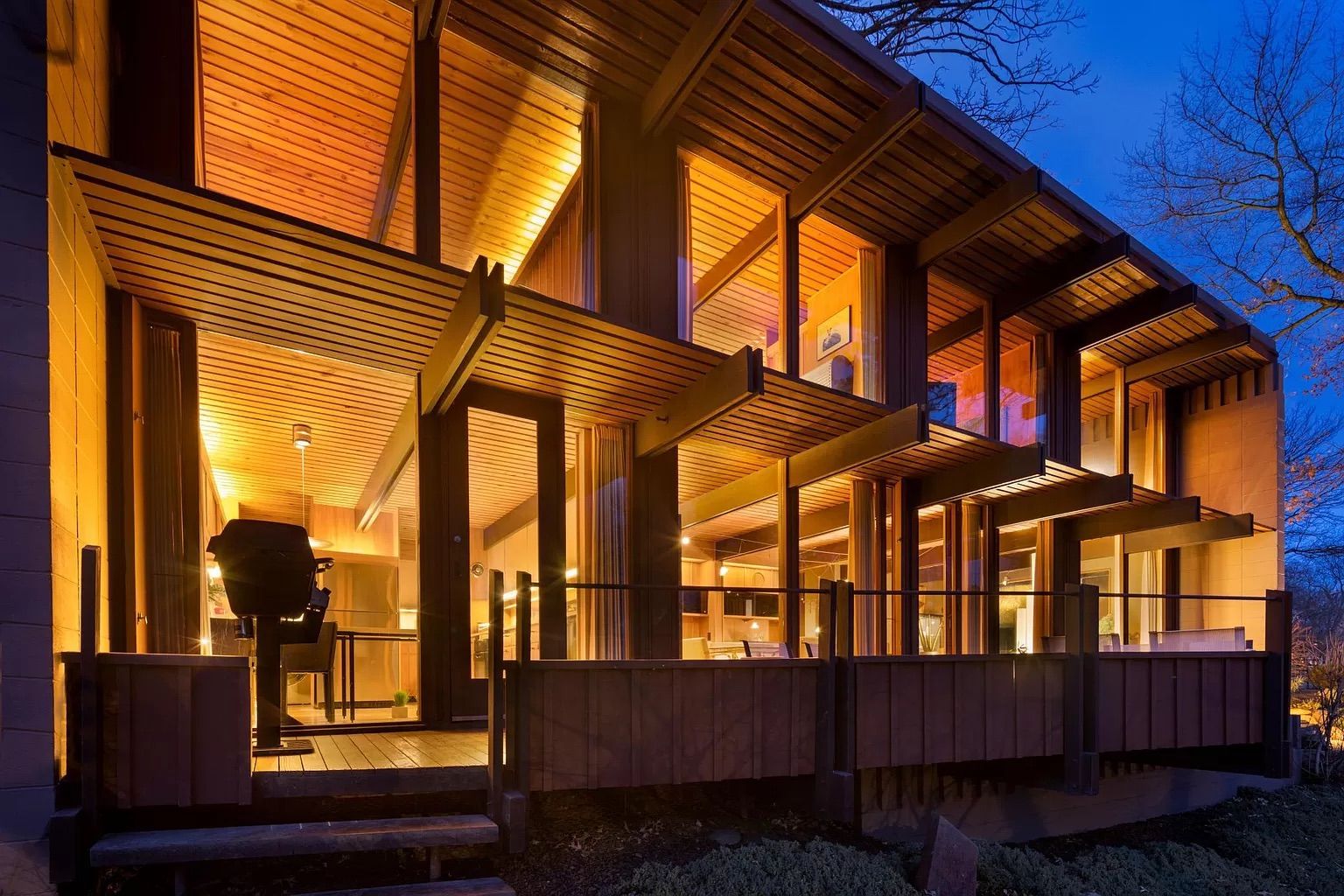 The back of a house with windows for walls seen at sunset.