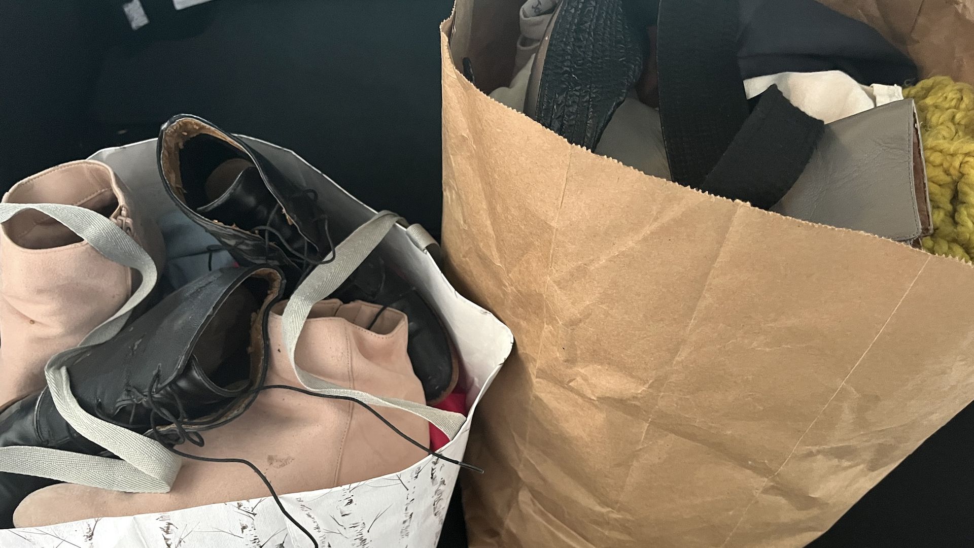 Two paper bags filled with clothes and shoes.