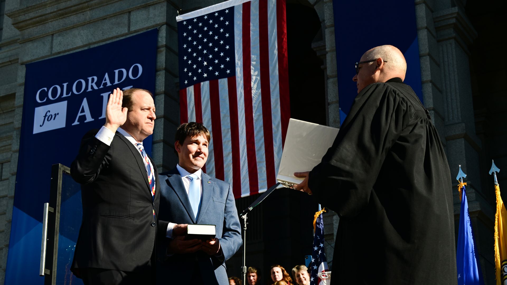 Colorado Supreme Court Chief Justice Brian Boatright, right, administers the oath of office to Gov. Jared Polis.