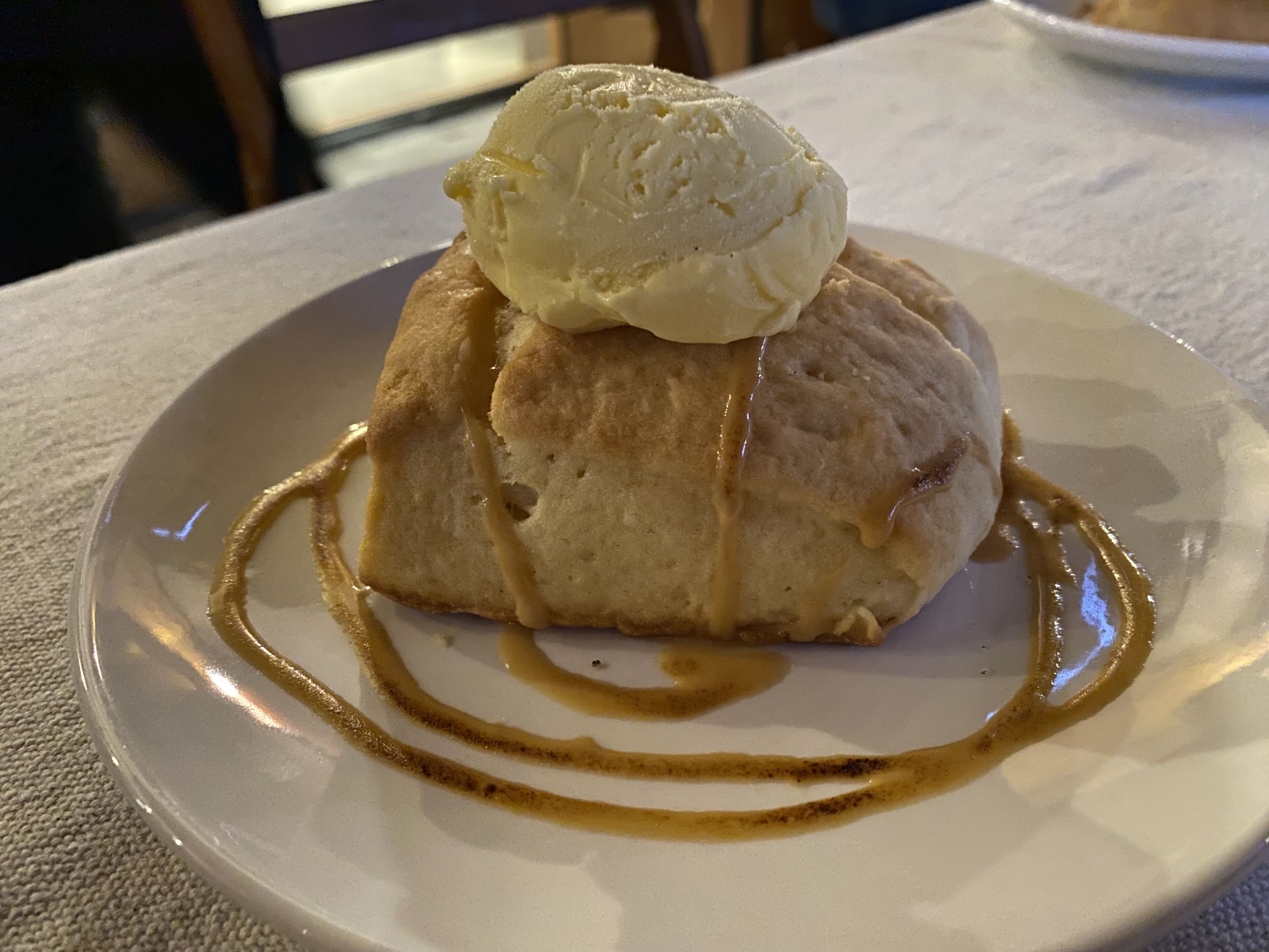 Photo of shortbread on a white plate topped with ice cream and a caramel swirl. 