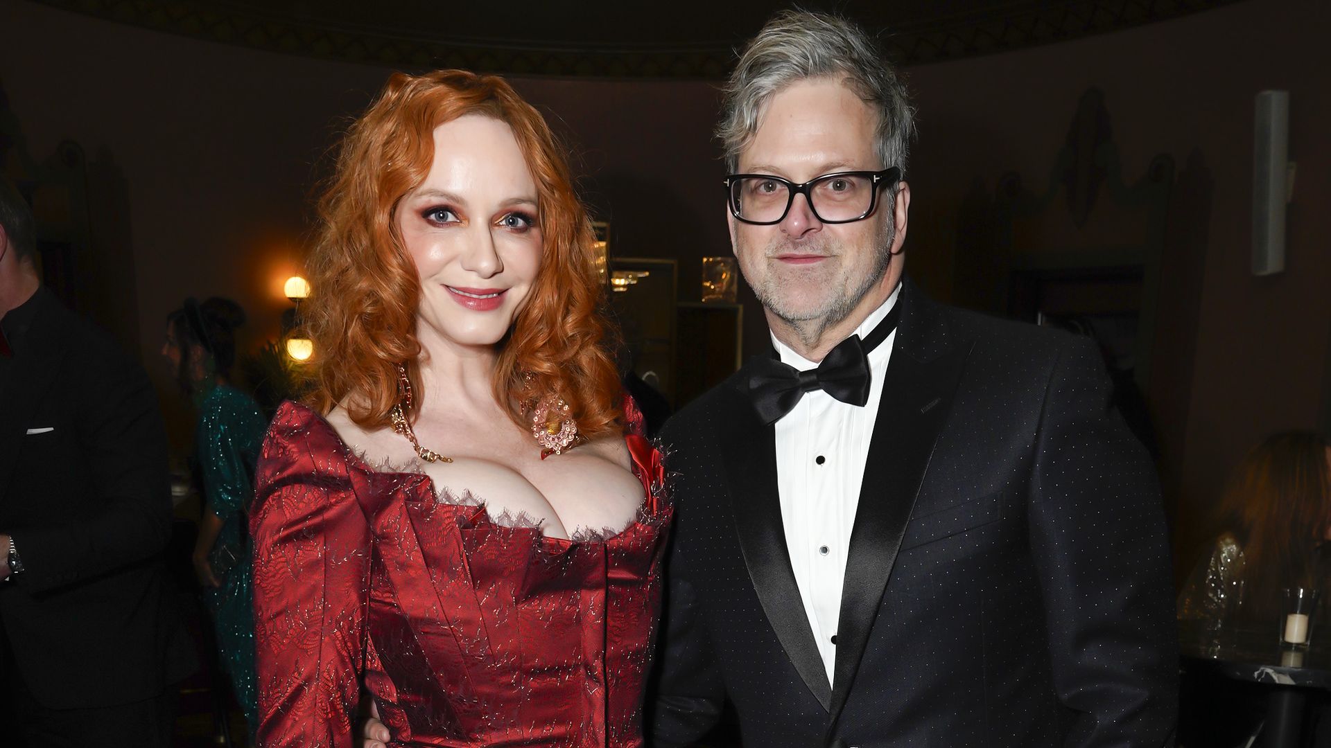Photo shows Christina Hendricks in a red dress next to George Bianchini in a black tuxedo.