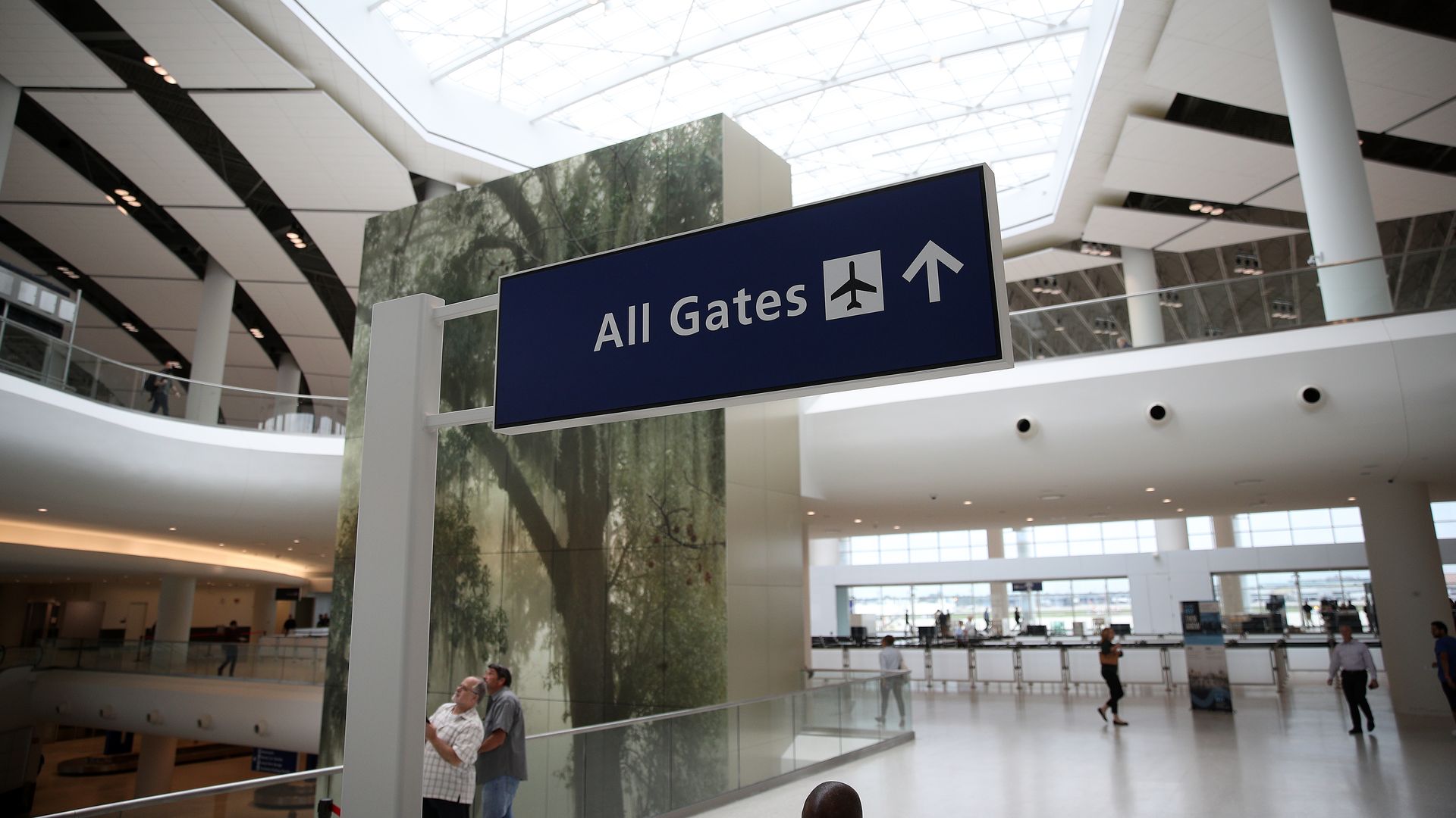 Image shows the inside of an airport with a sign that says "all gates" and an arrow pointing straight ahead.