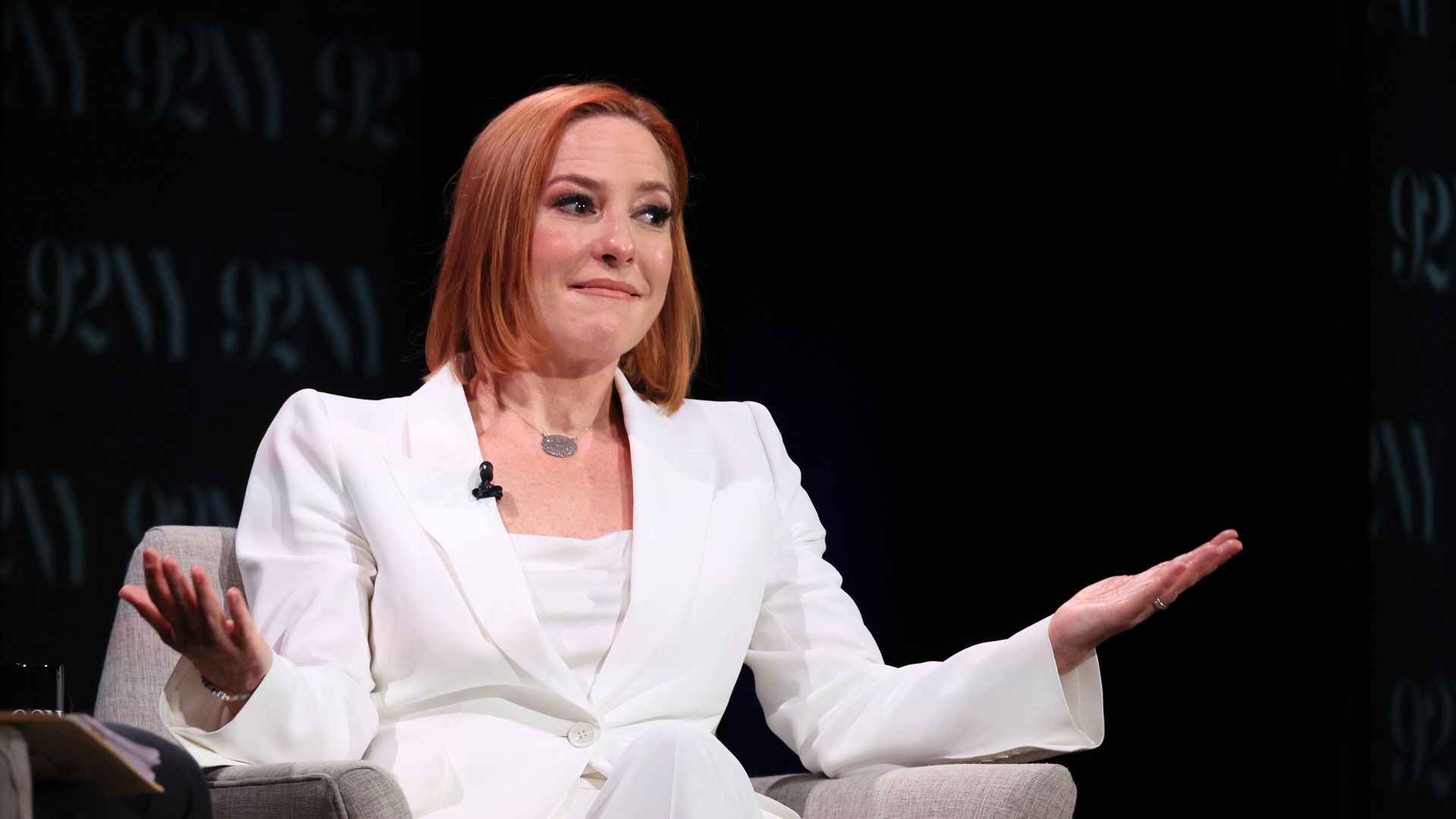 Jen Psaki in a white suit, with open arms