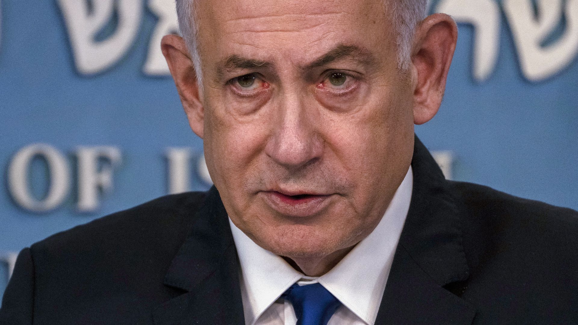Benjamin Netanyahu, wearing a dark blue suit, white shirt and blue tie.