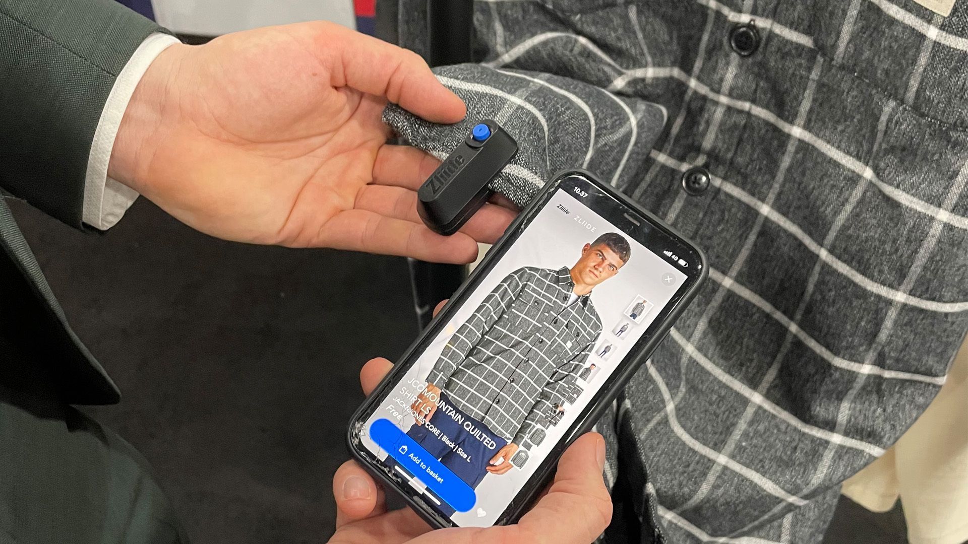 A digital fob attached to a shirt with an iphone next to it.