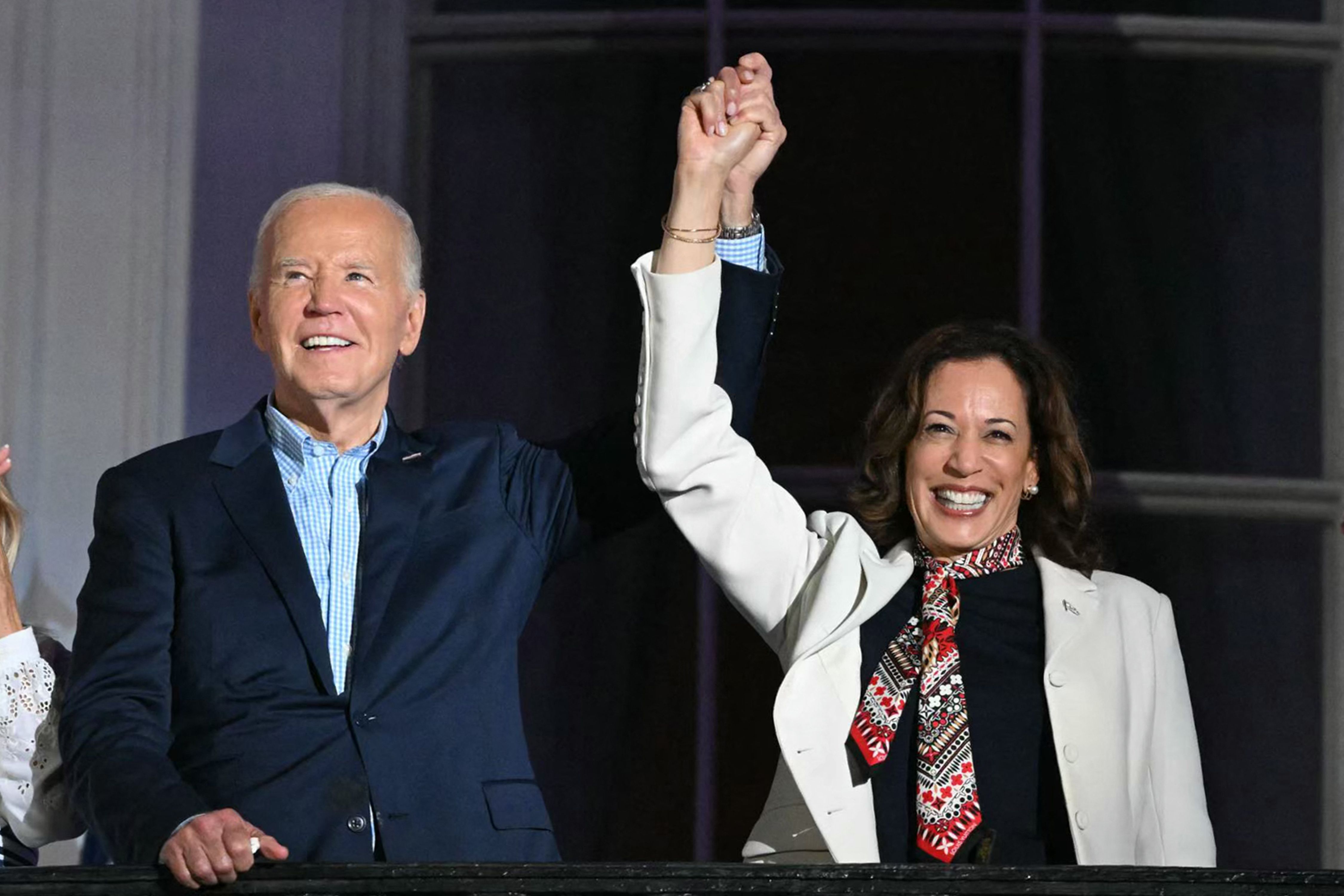 TOPSHOT - US President Joe Biden (L) holds hands with US Vice President Kamala Harris as they arrive to watch the Independence Day fireworks display from the Truman Balcony of the White House