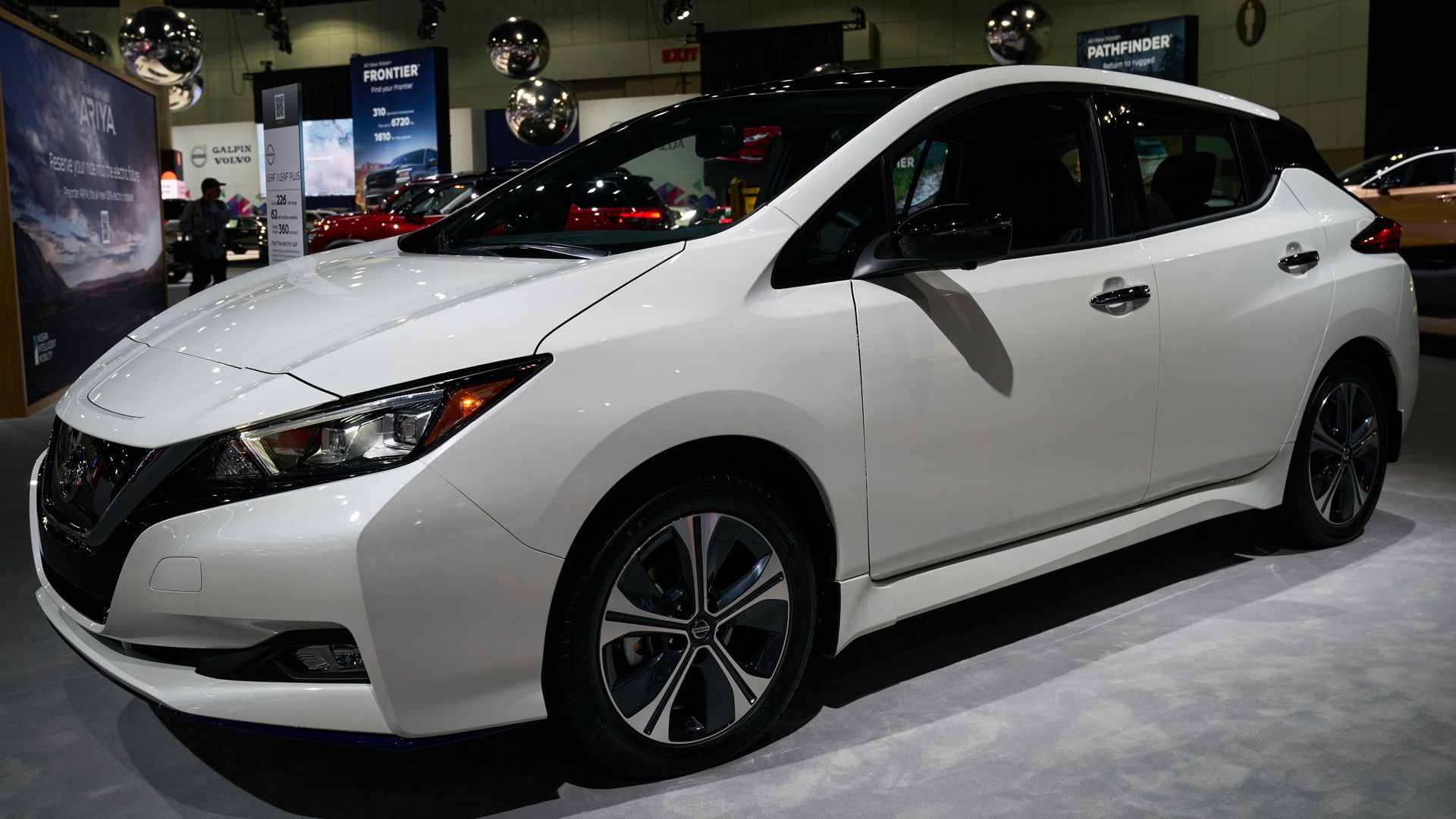 A white car sits on the floor of an automotive show