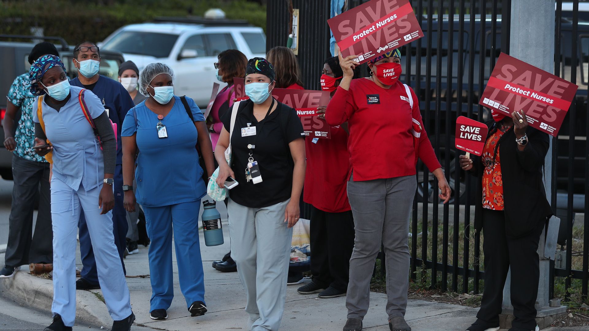 Healthcare workers on their way to work walk past demonstrators who are taking part in a national day of action to save lives during COVID-19 on August 05, 2020 in Miami, Florida.