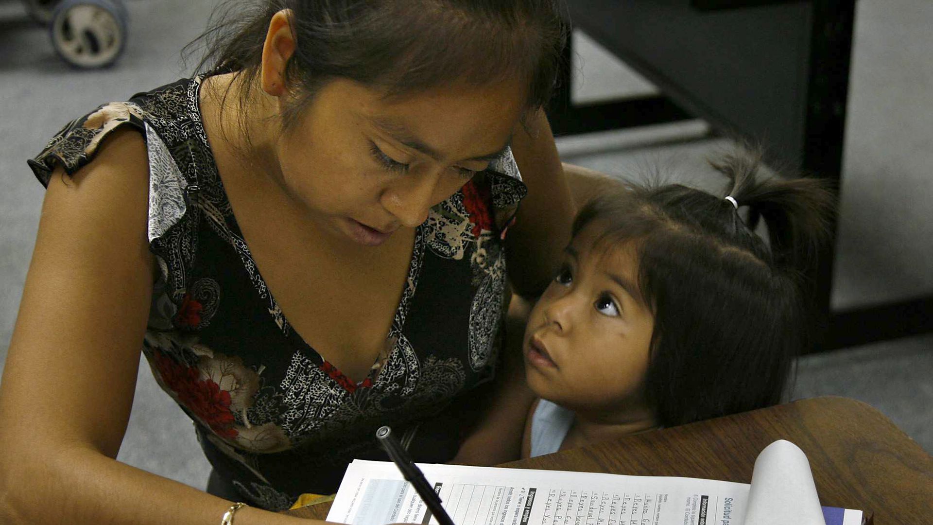 A woman and her child fill out an application for food stamps.