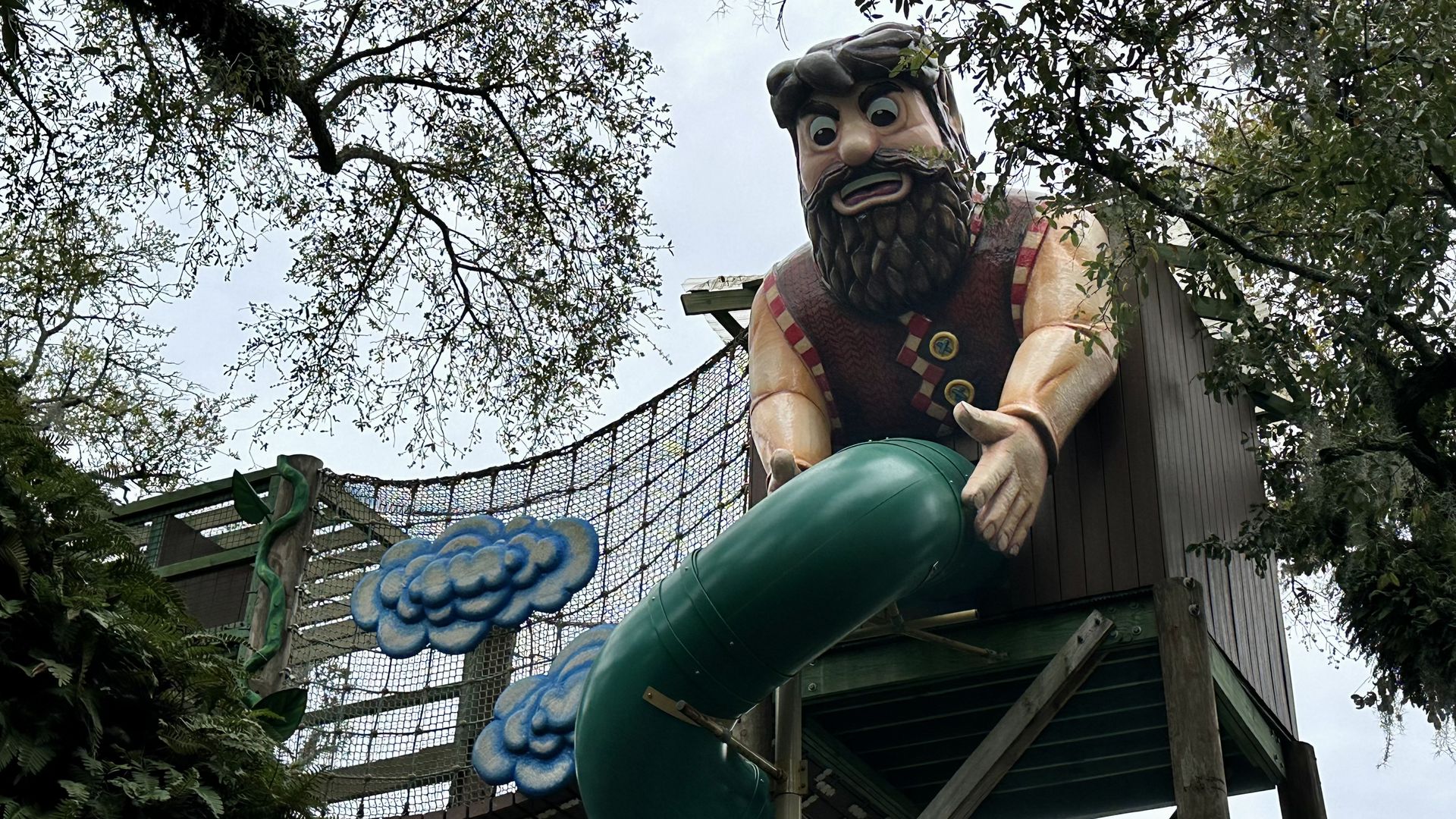 Photo shows the giant from "Jack and the Beanstalk" holding a green slide in what could be construed as a suggestive pose.