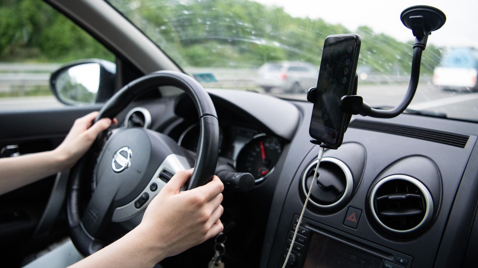 A woman sits in the car with her  cell phone in a holder. This is the only legal way to use your phone while driving in Michigan starting tonight. Photo by Melissa Erichsen