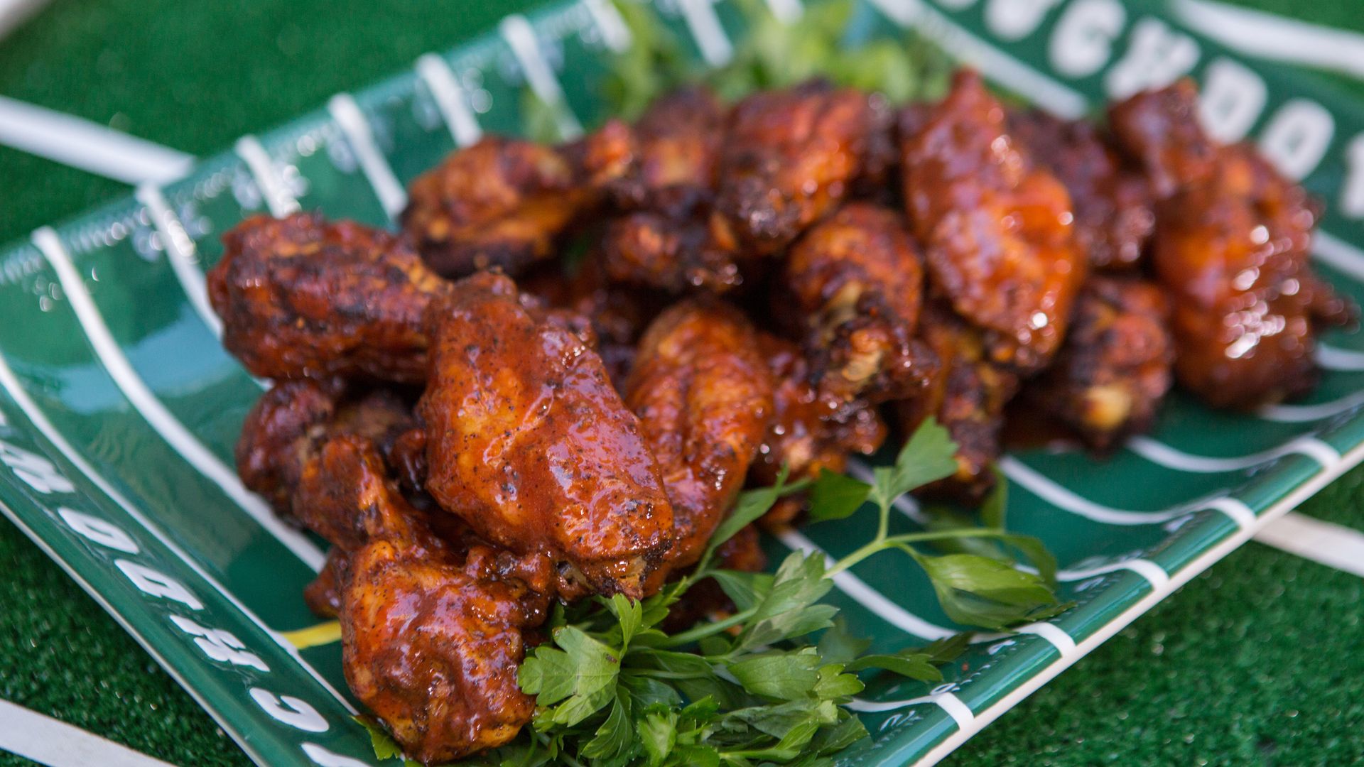 Chicken wings on a green platter plate that looks like a football field
