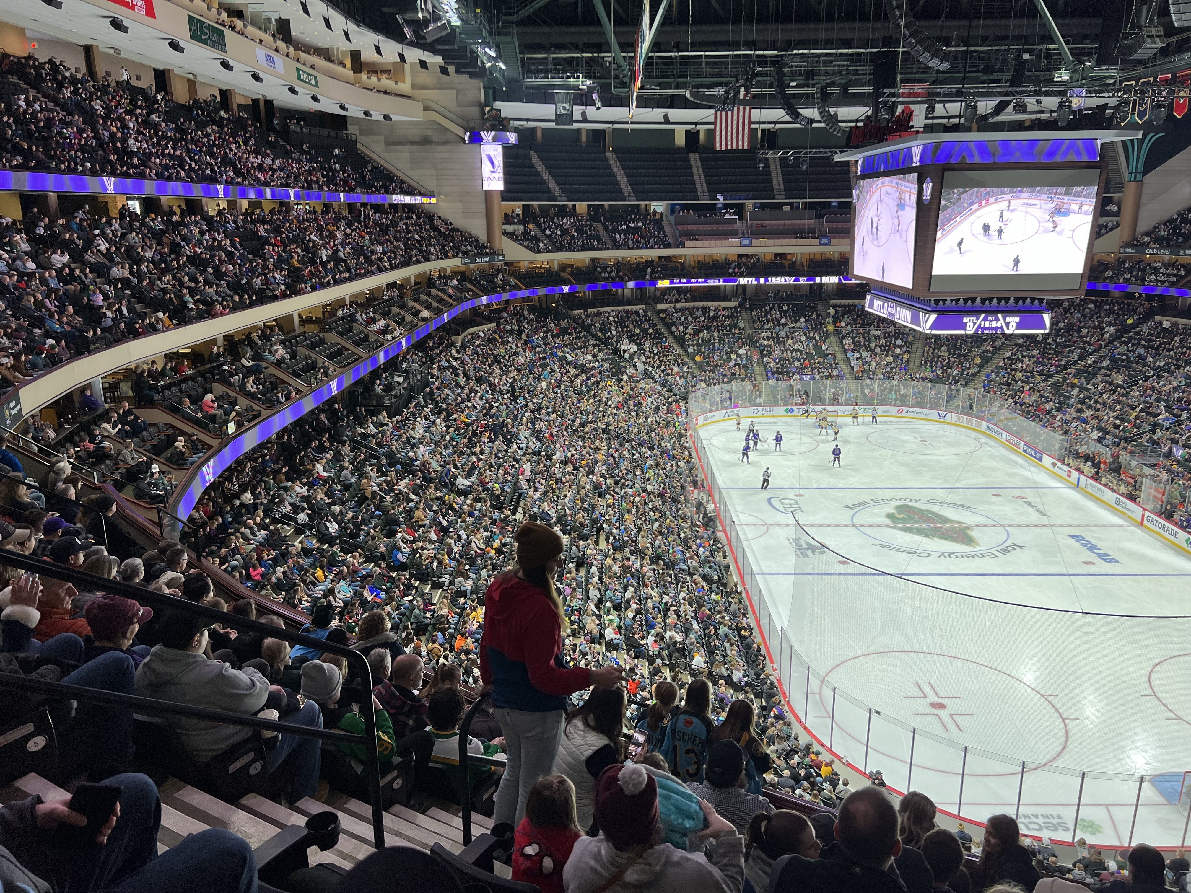 A fan searches for her seat in a large professional hockey arena.