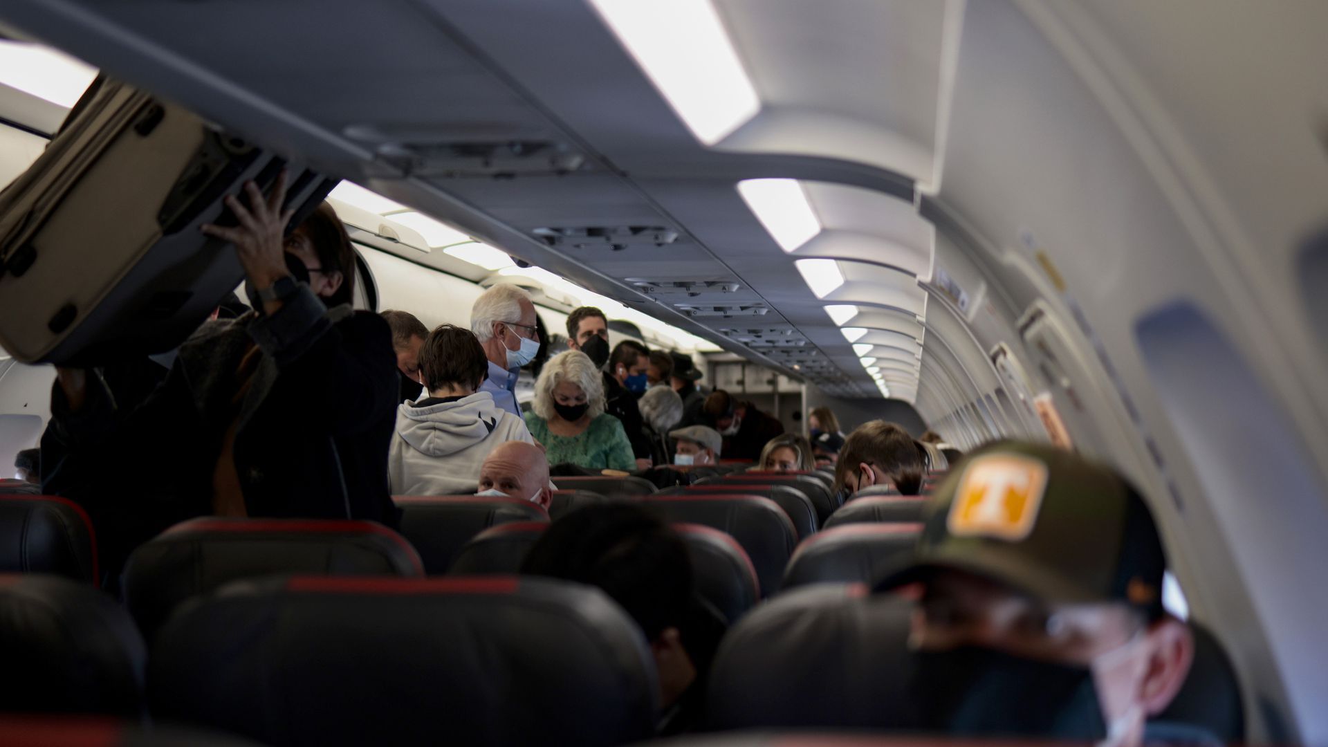 people seen retrieving luggage from overhead bins on an airplane.