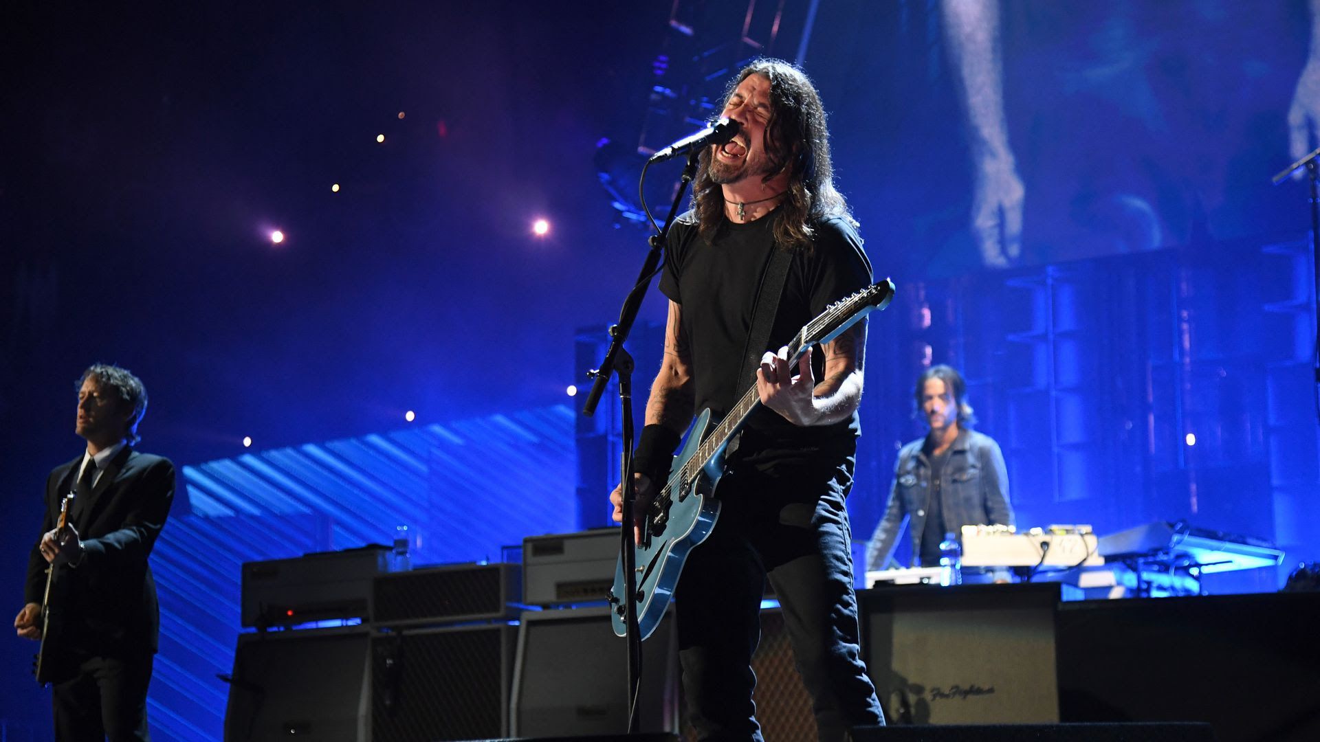 Dave Grohl of the Foo Fighters sings into the mic on stage.