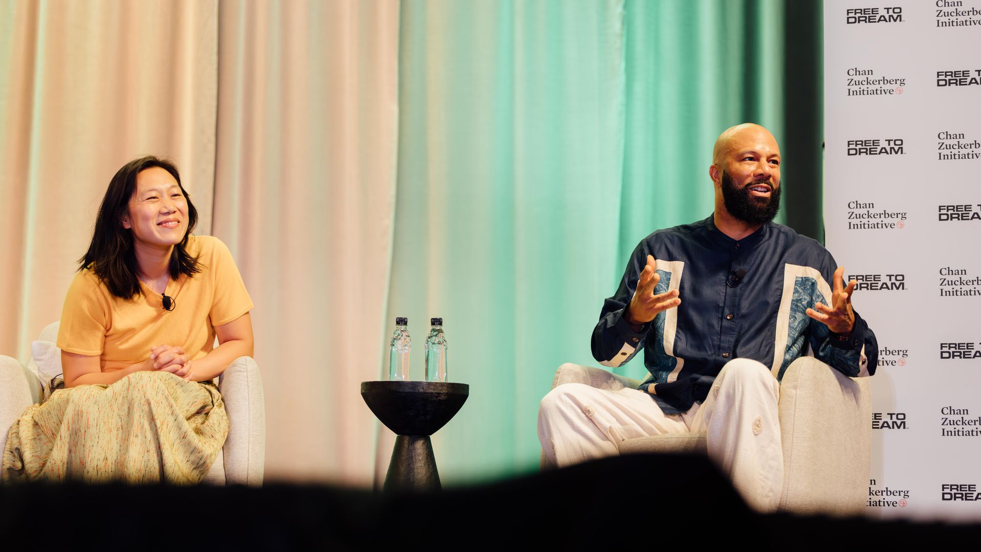 Photo of two people on stage talking to an audience 