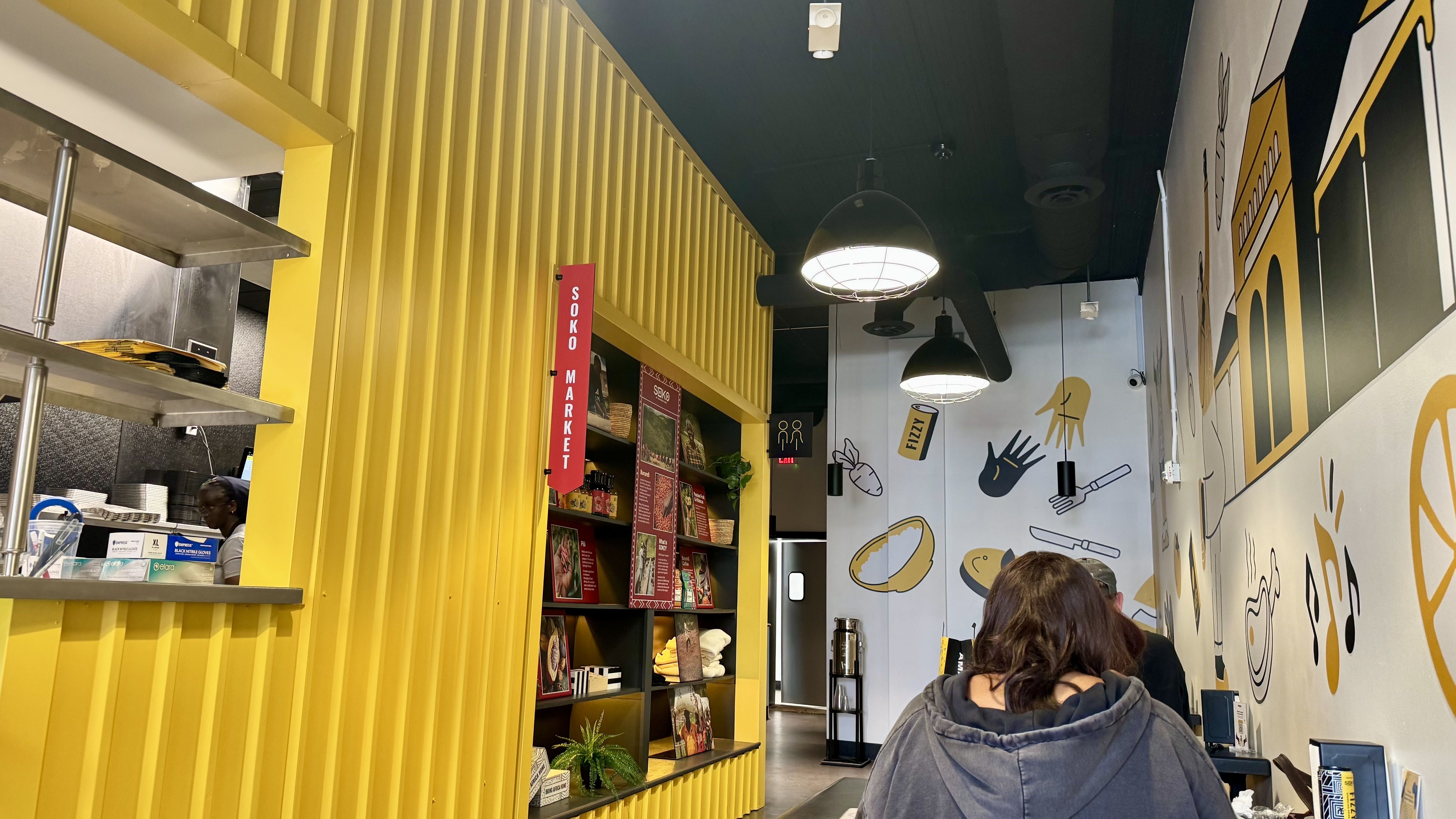 One yellow wall and another wall with art on it. 
