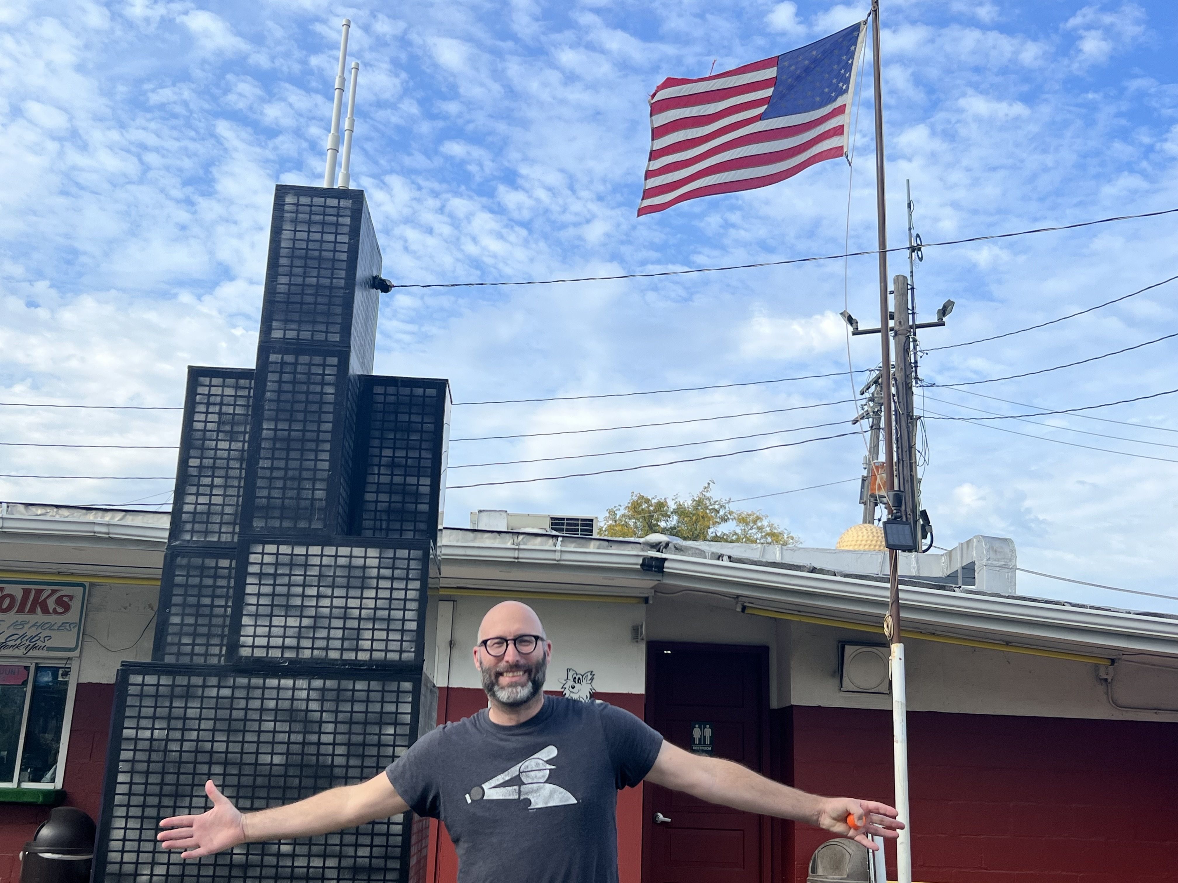 Photo of a man in front of a fake building and a flag