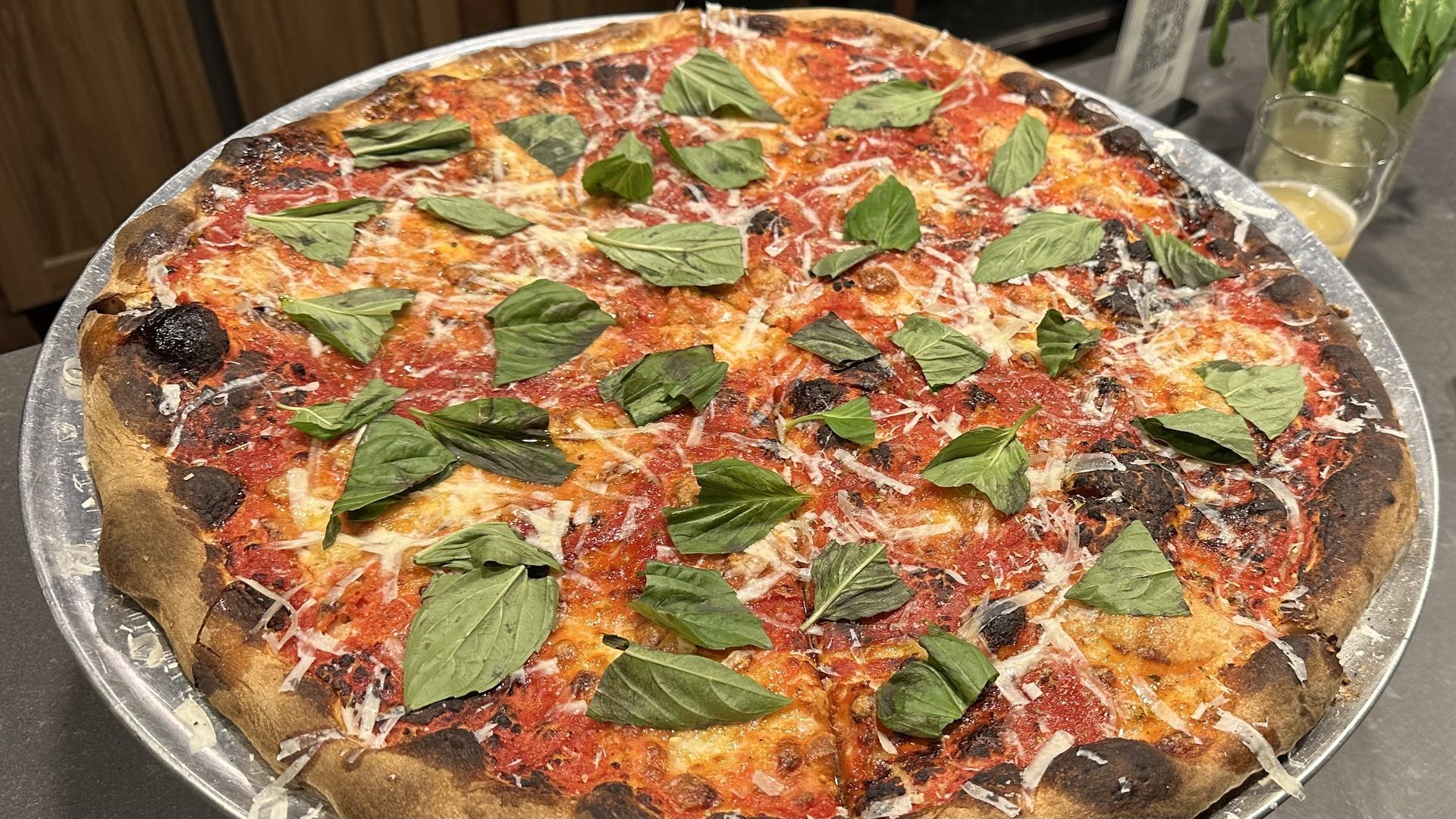 A photo of a large Margherita pizza on a silver tray.