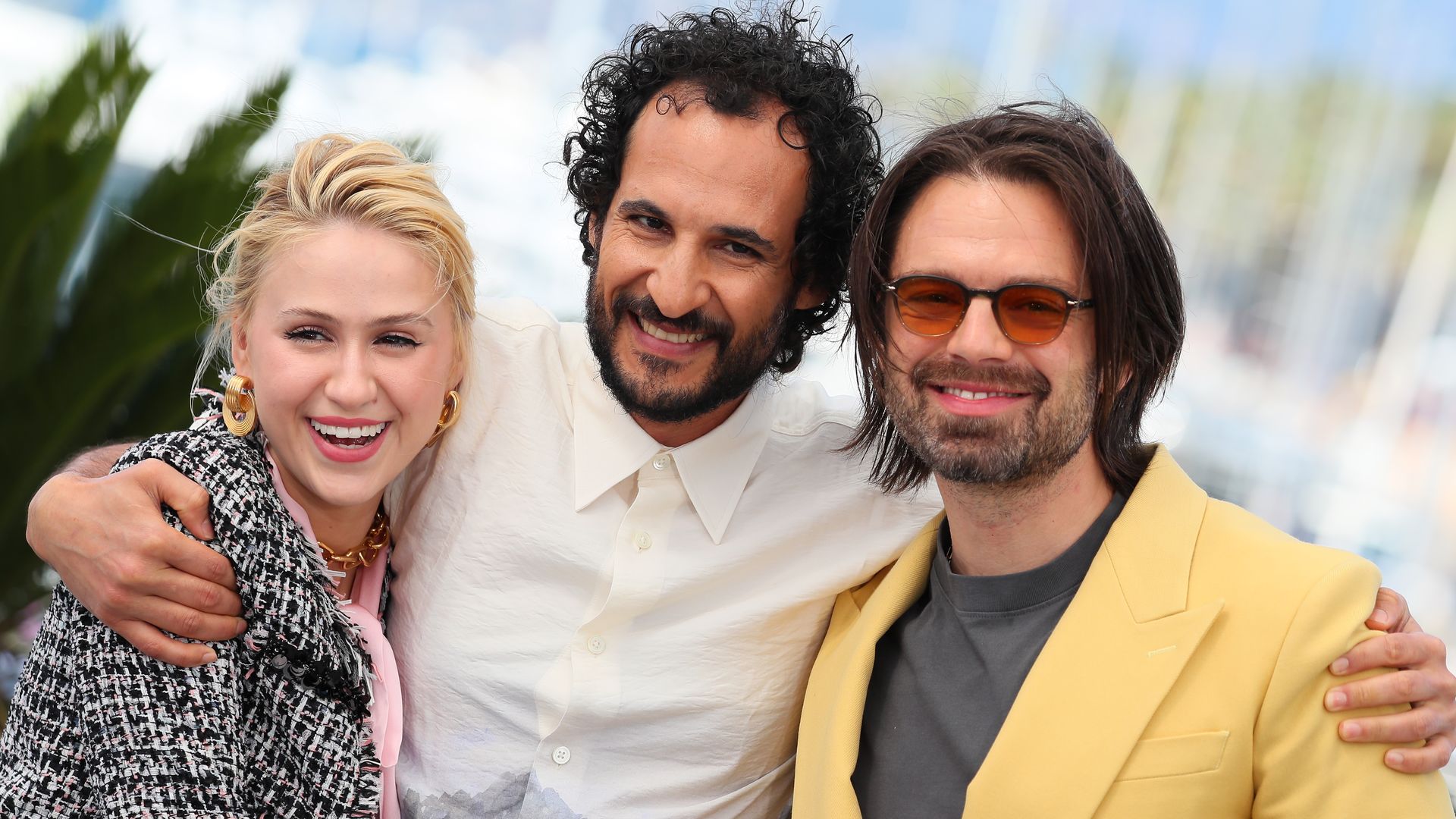 A man stands in between a woman and another man, with his arms around them.