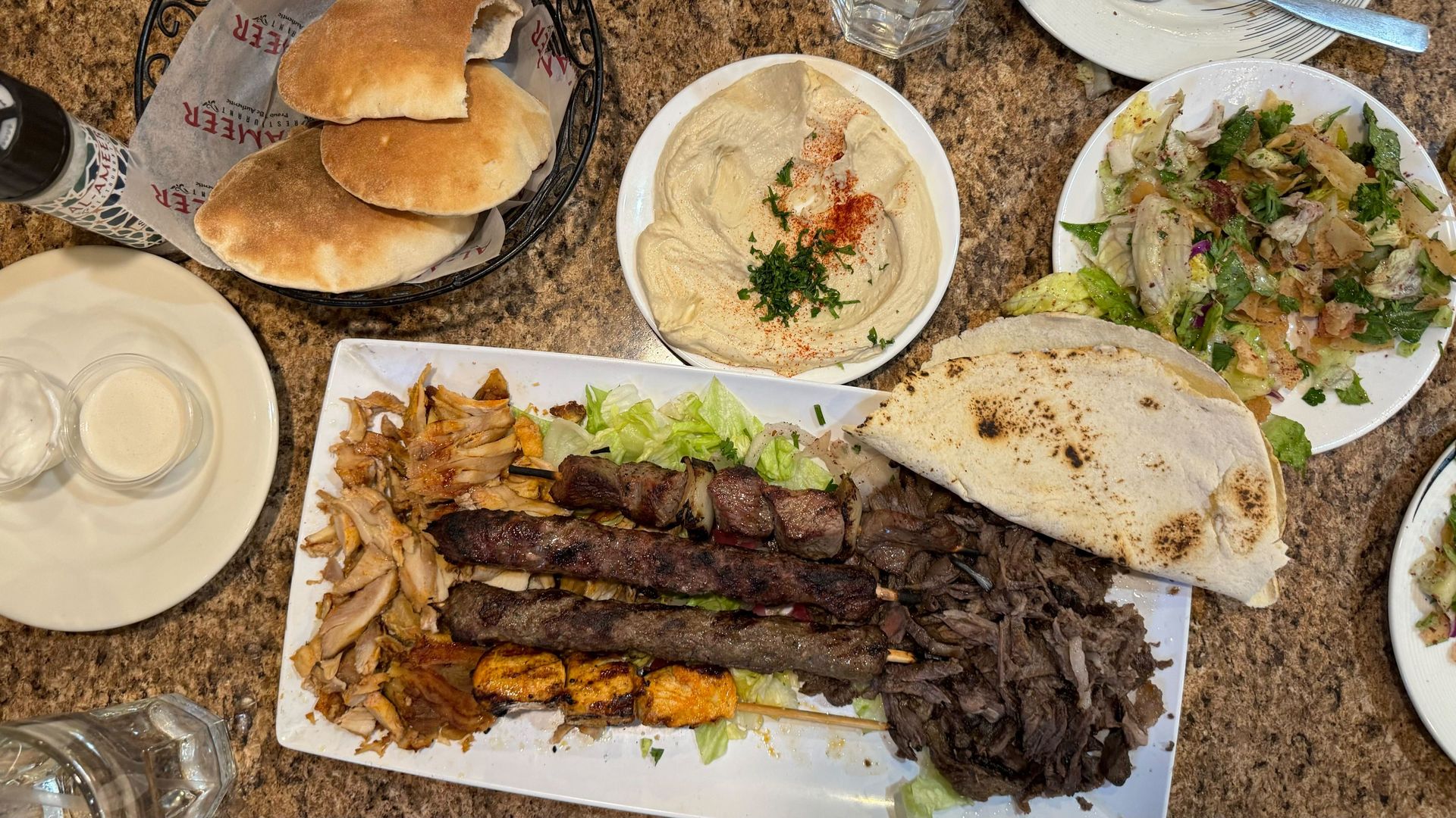 Plates with bread, salad, hummus and meat. 