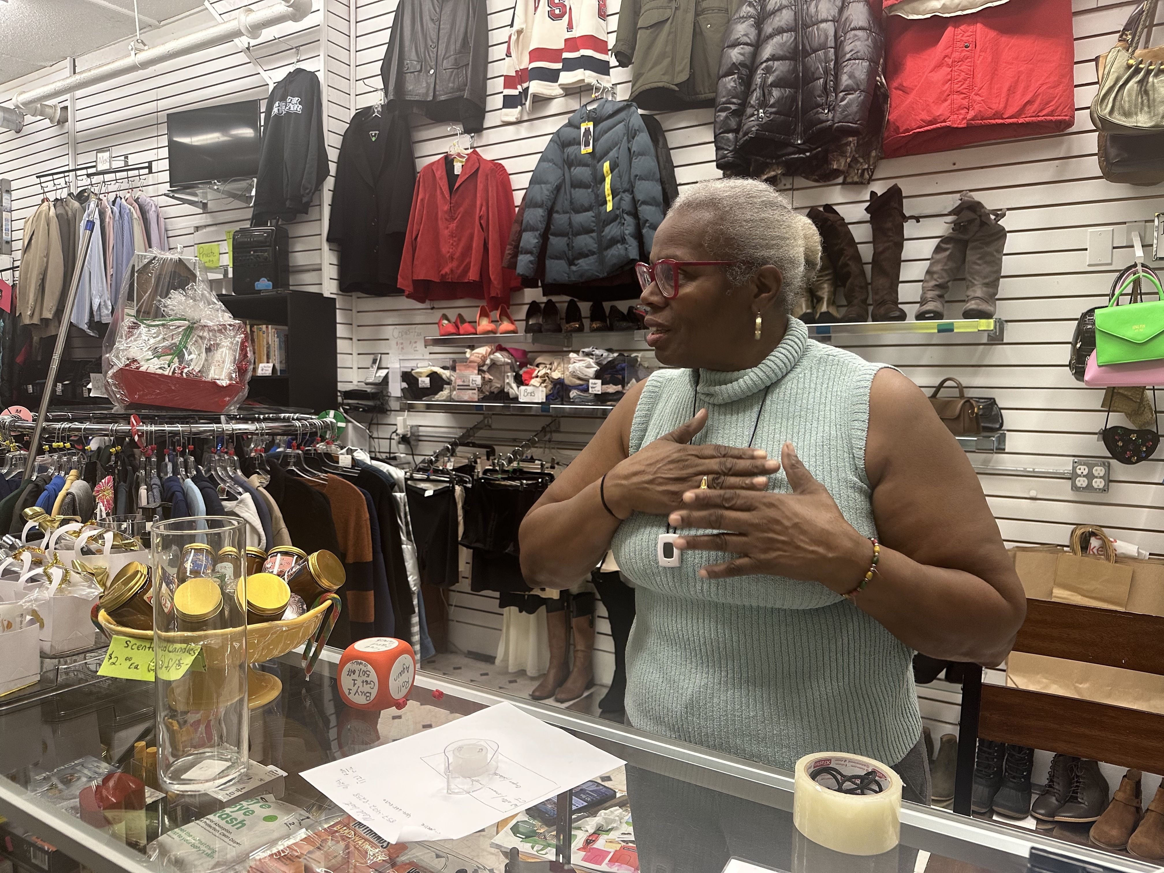 Deborah Cox, owner of DAC Thrift Shop in Dorchester, speaks from behind the counter. 