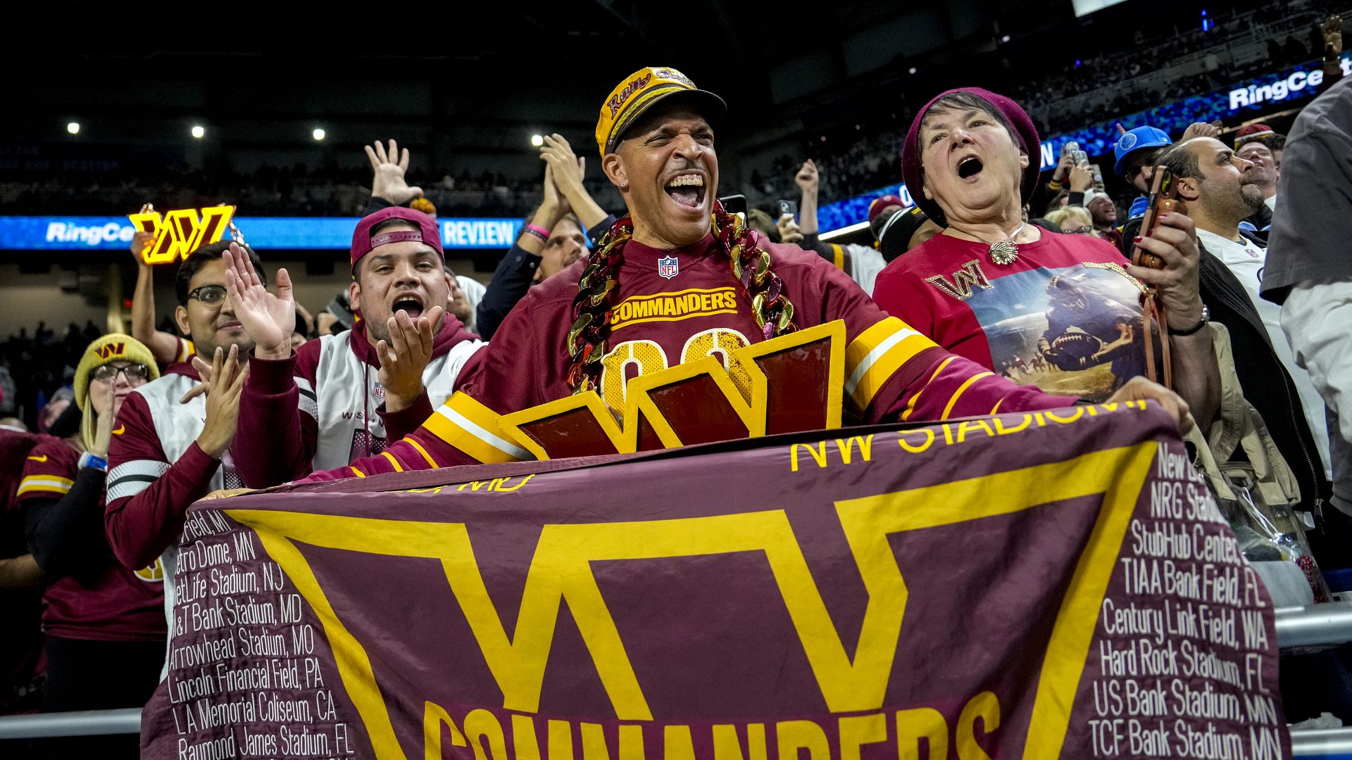fans of the Washington Commanders hold up a burgundy and gold flag