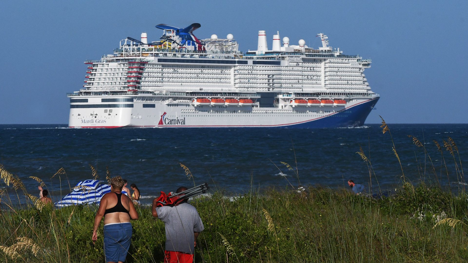 People come out to watch the new Carnival Cruise Line ship Mardi Gras as it departs on its maiden voyage, a seven-day cruise to the Caribbean from Port Canaveral, Florida on July 31, 2021.