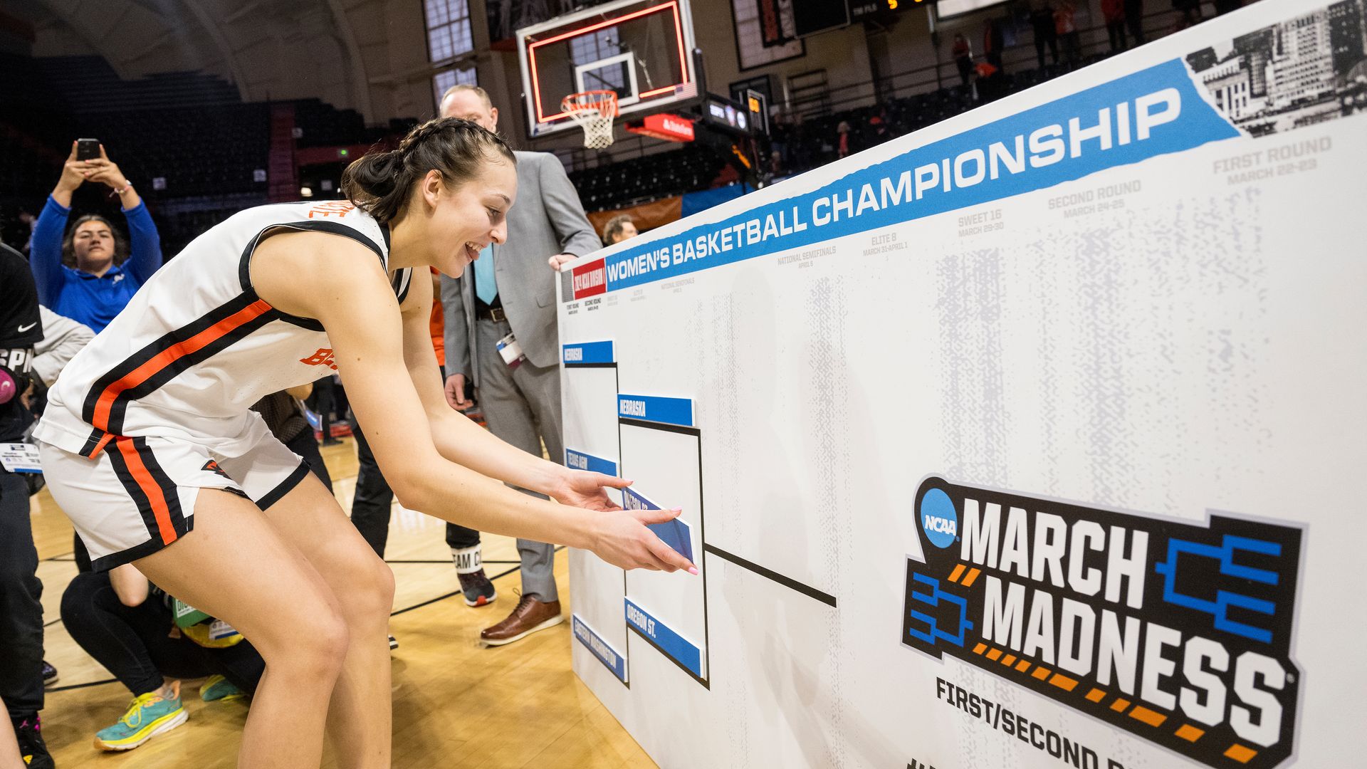 AJ Marotte of the Oregon State women's basketball team places a sticker on a March Madness bracket.