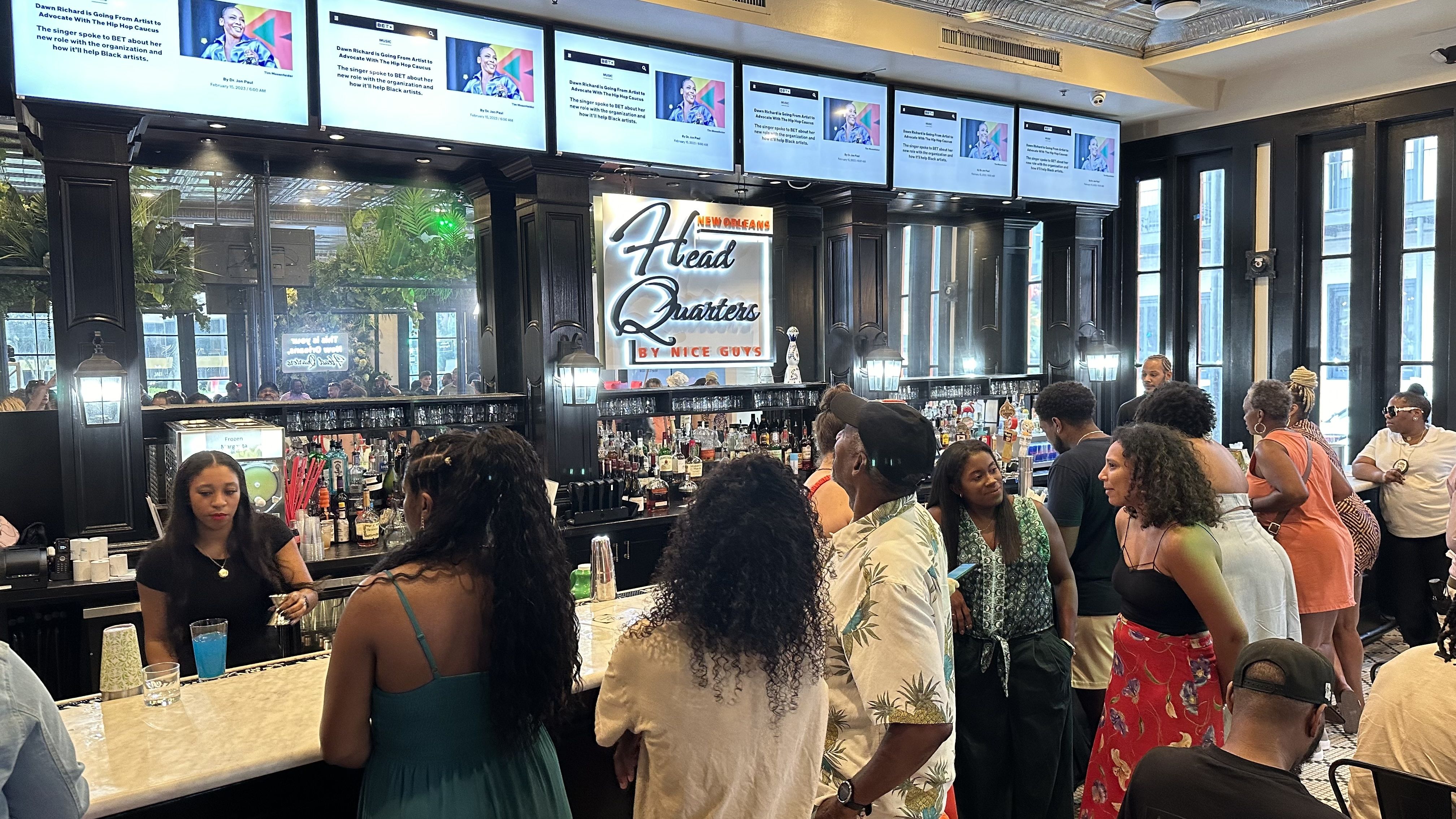 A bartender mixes a drink at the packed bar inside Headquarters by Nice Guys NOLA.