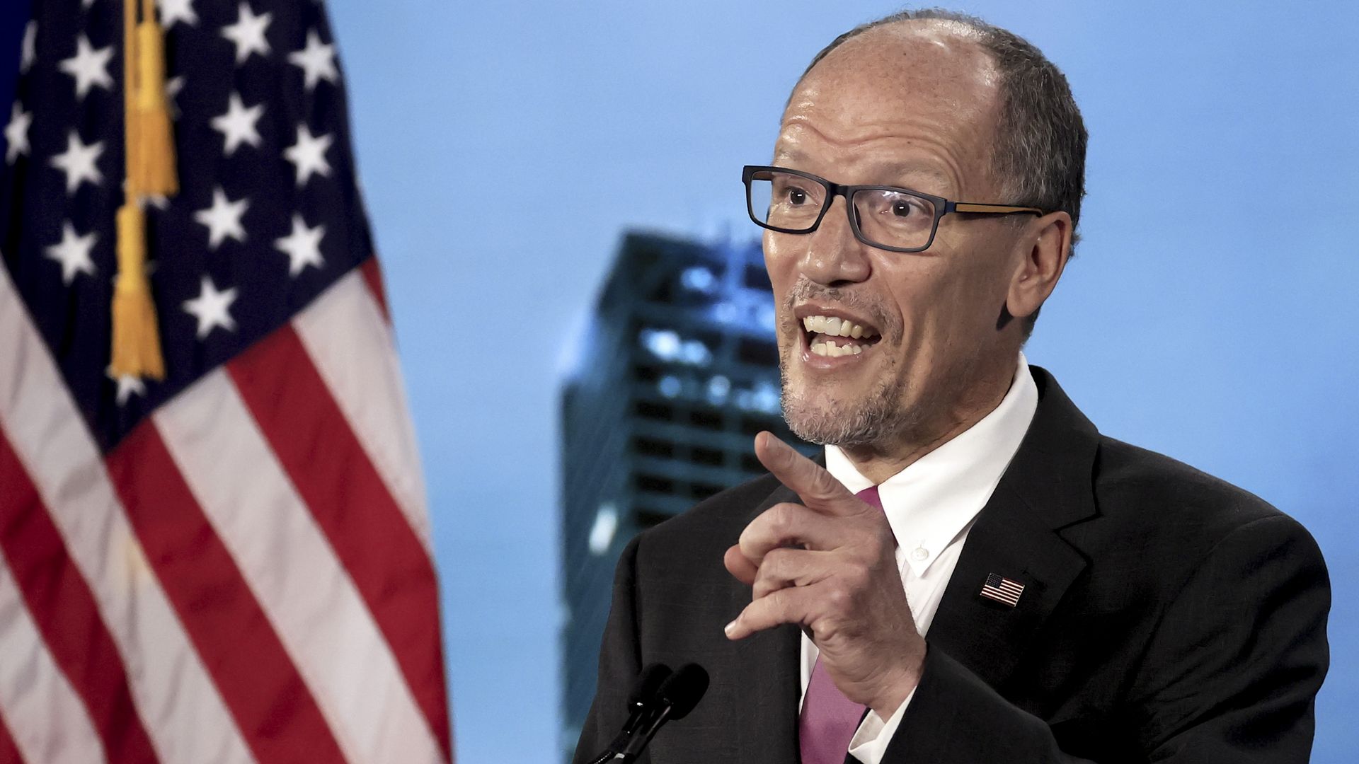 Tom Perez wears glasses and a suit 