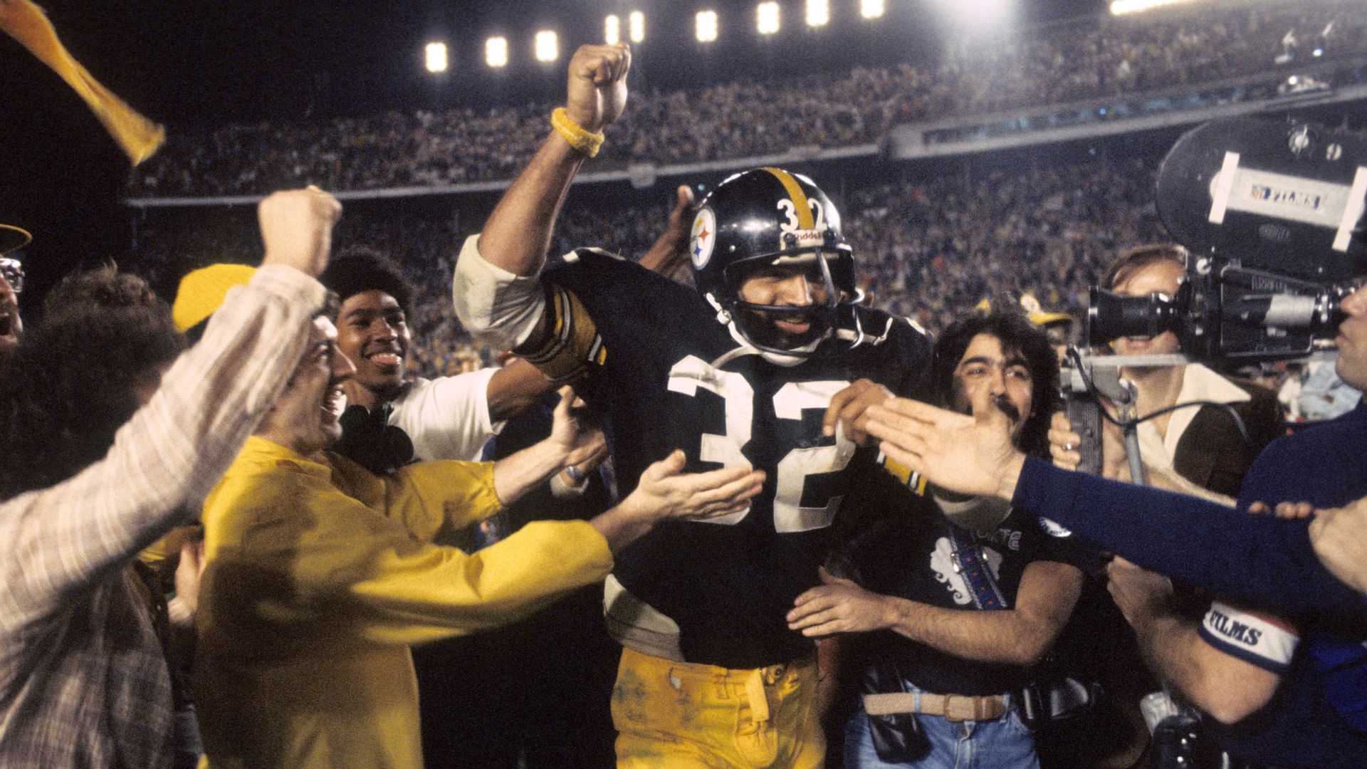 Steelers legend Franco Harris runs through a crowd of fans and media. 