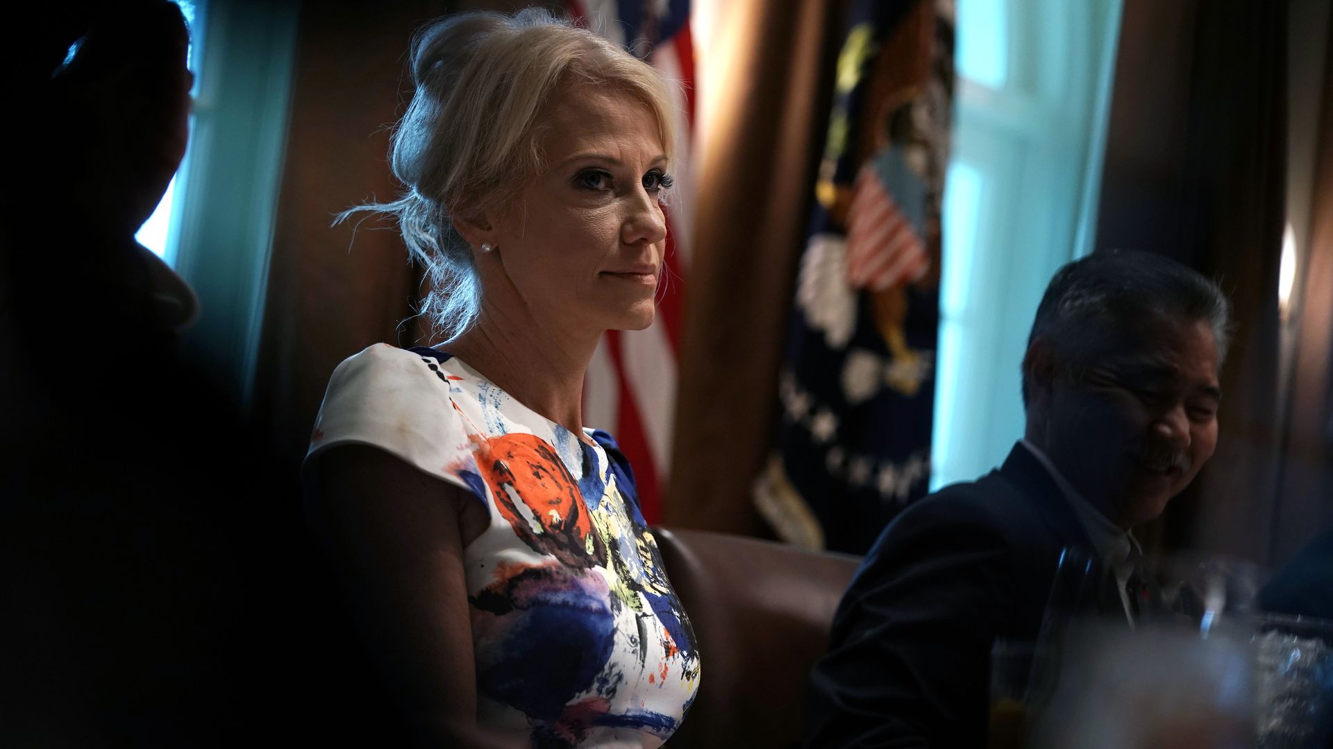 Kellyanna Conway looking ahead wearing a white dress with a watercolor print. 