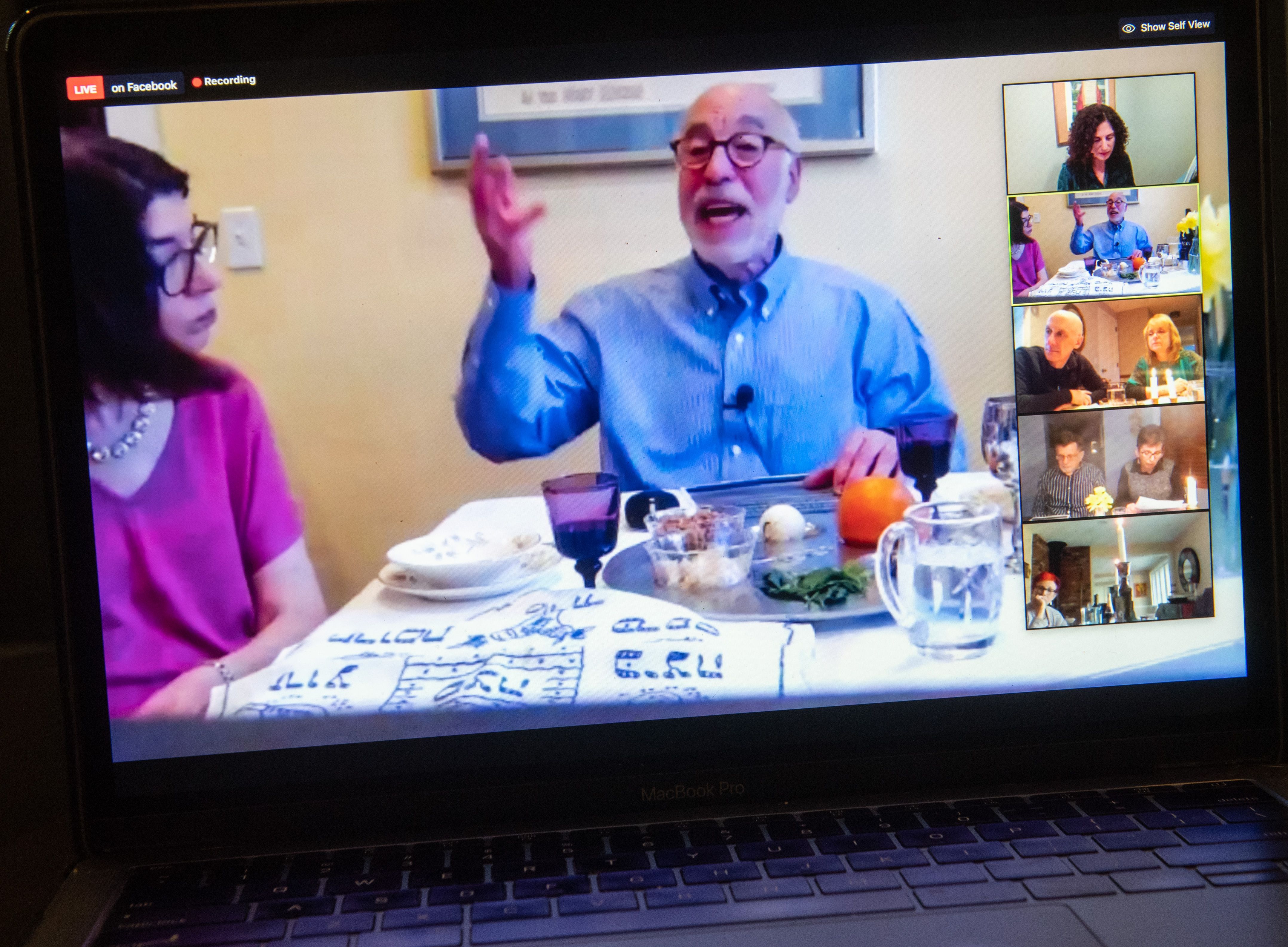 This image shows a man on a laptop screen during Seder