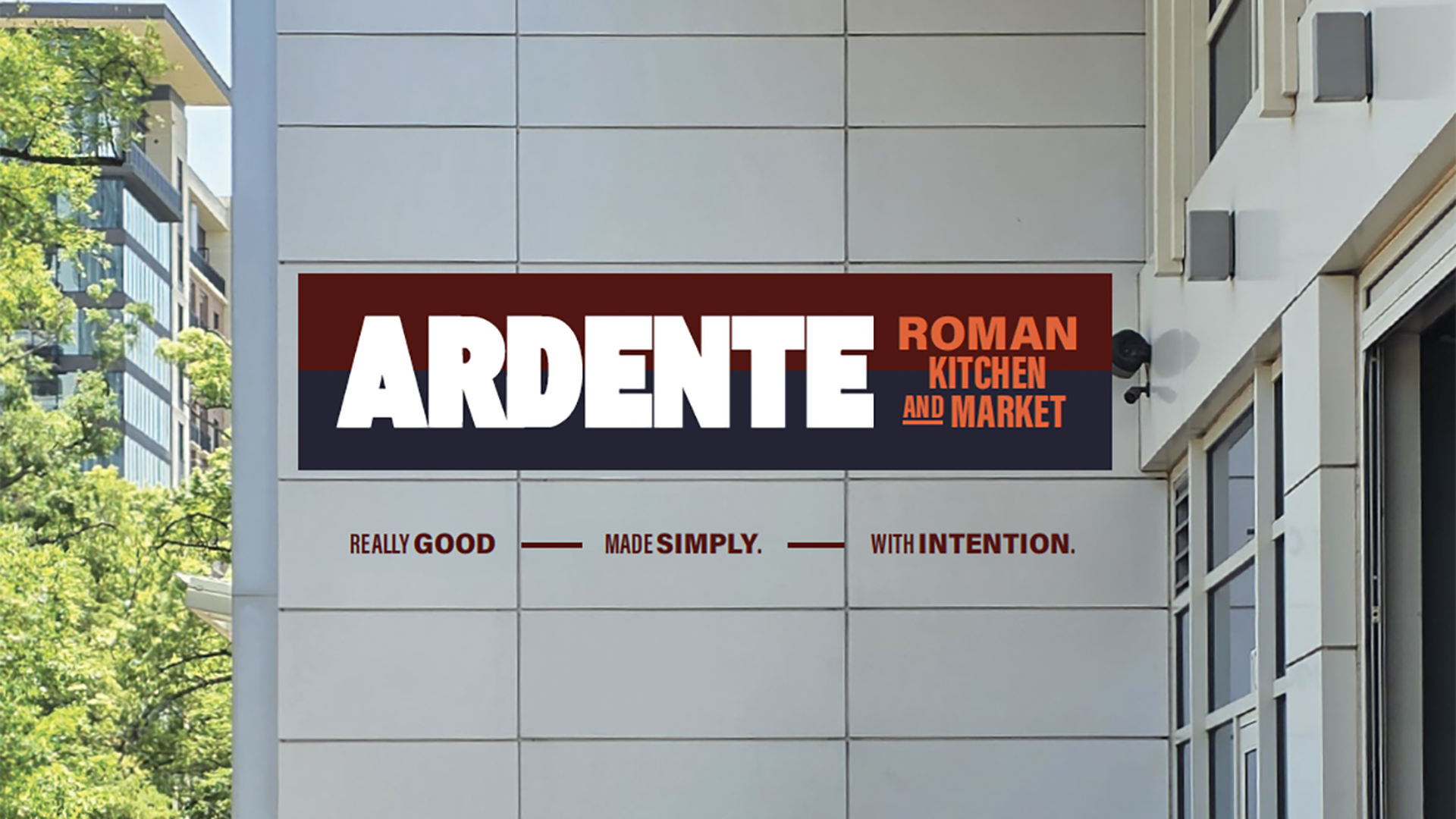 Outdoor dining area beside a white building, featuring a large ARDENTE sign with white letters on a red and navy background that reads ARDENTE ROMAN KITCHEN AND MARKET; patrons sit at tables outside.