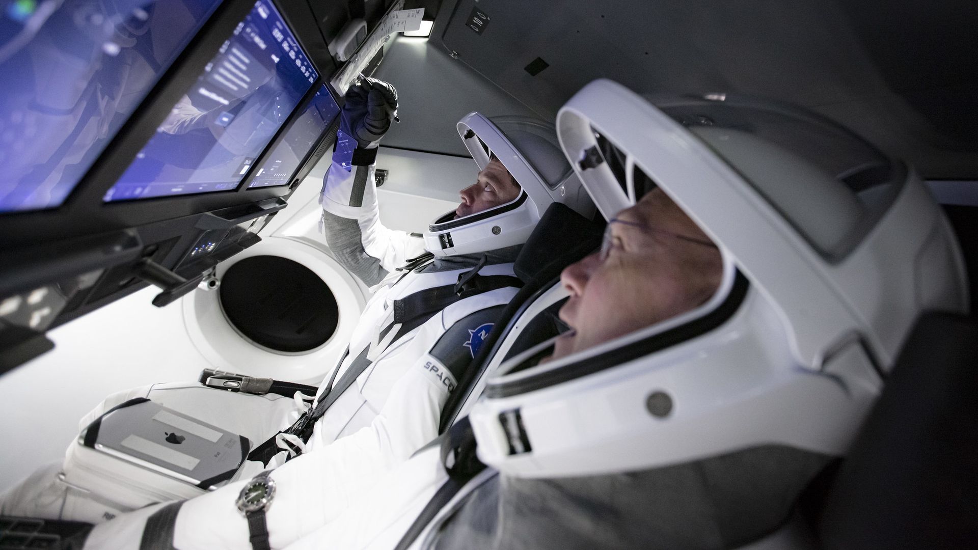 NASA astronauts Bob Behnken and Doug Hurley working inside SpaceX's Crew Dragon.