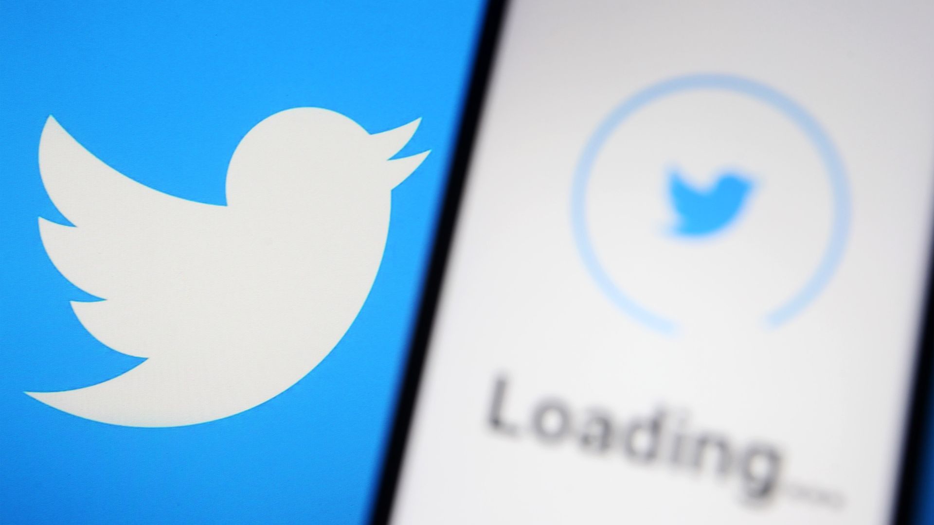 A photo of two screens displaying the Twitter logo, with one also displaying a loading message