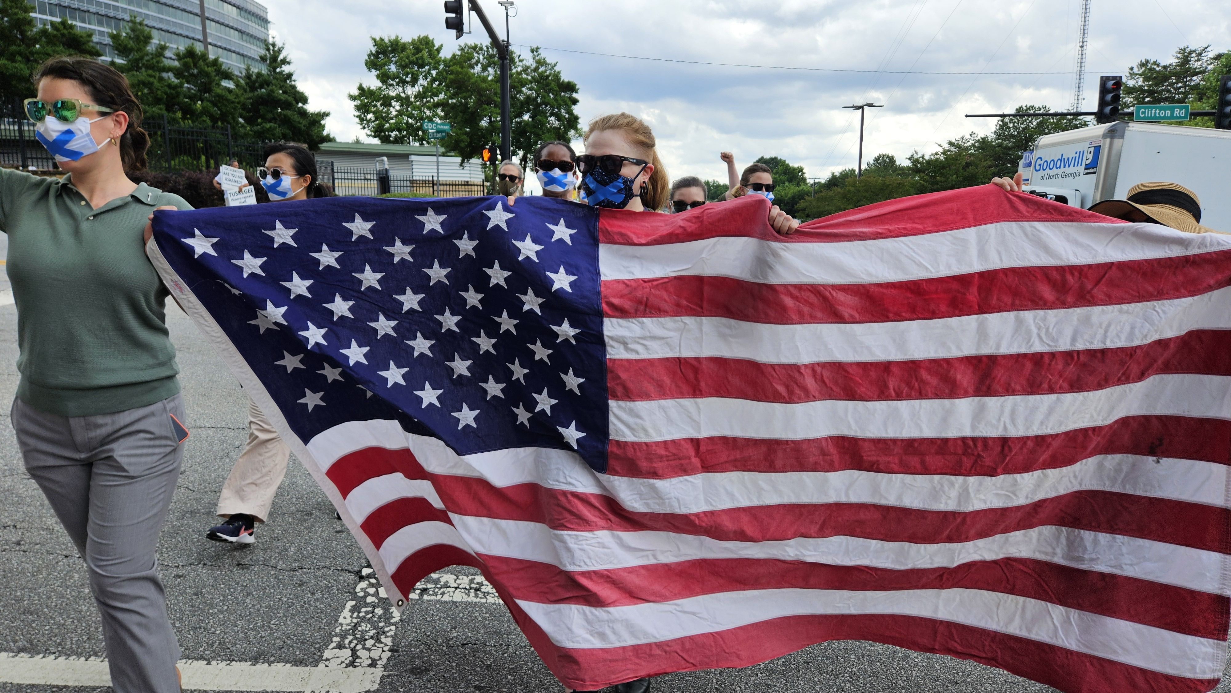 Protesters wearing face masks carry a large U.S. flag