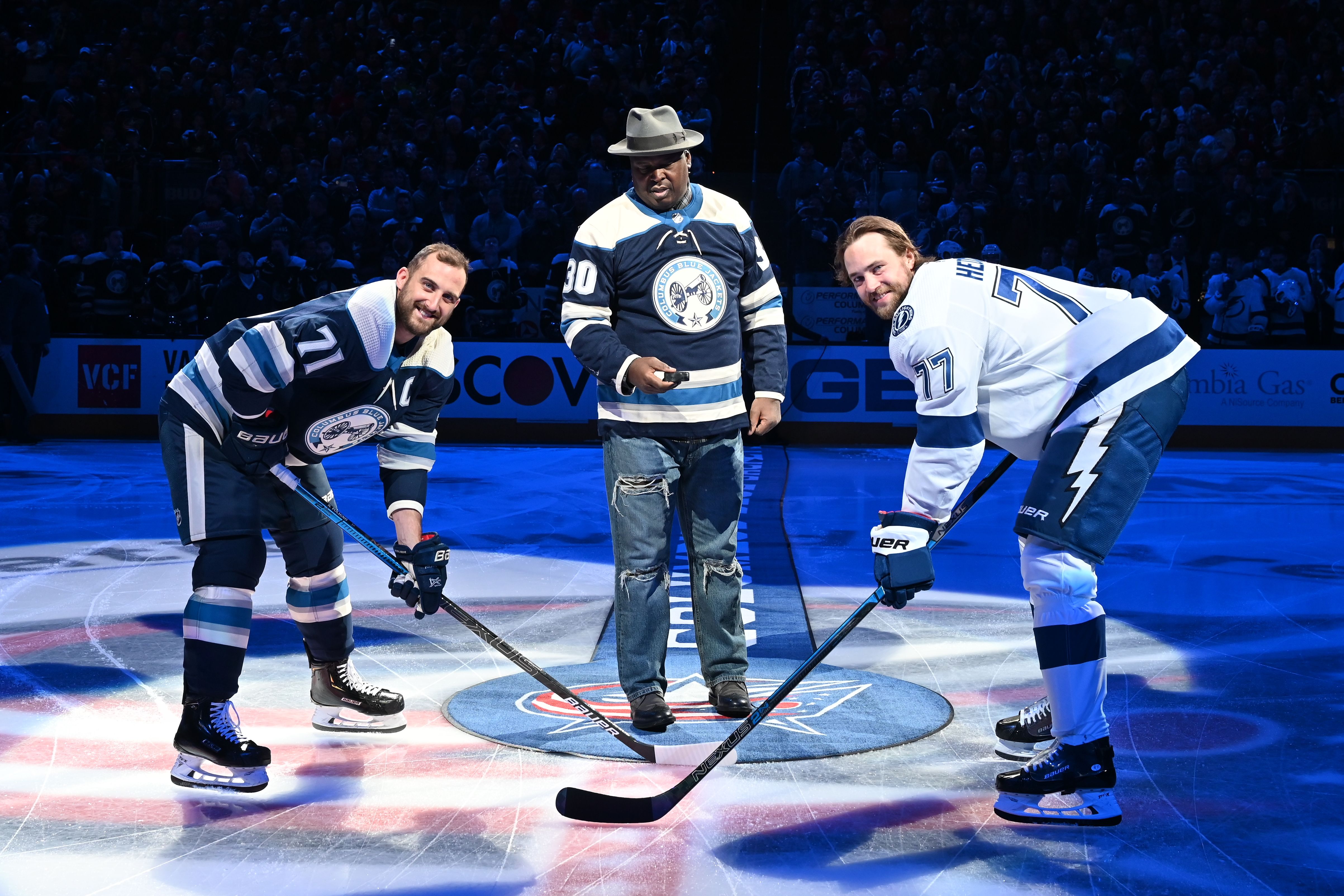 Buster Douglas stands on the ice between two hockey players for a ceremonial puck drop. 