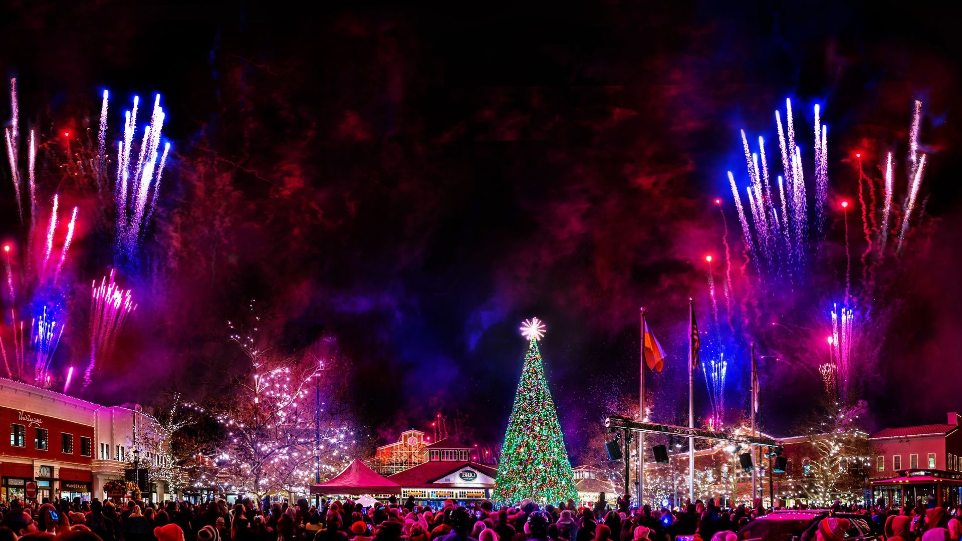 Fireworks launch into the sky on both sides of a giant illuminated Christmas tree at Easton