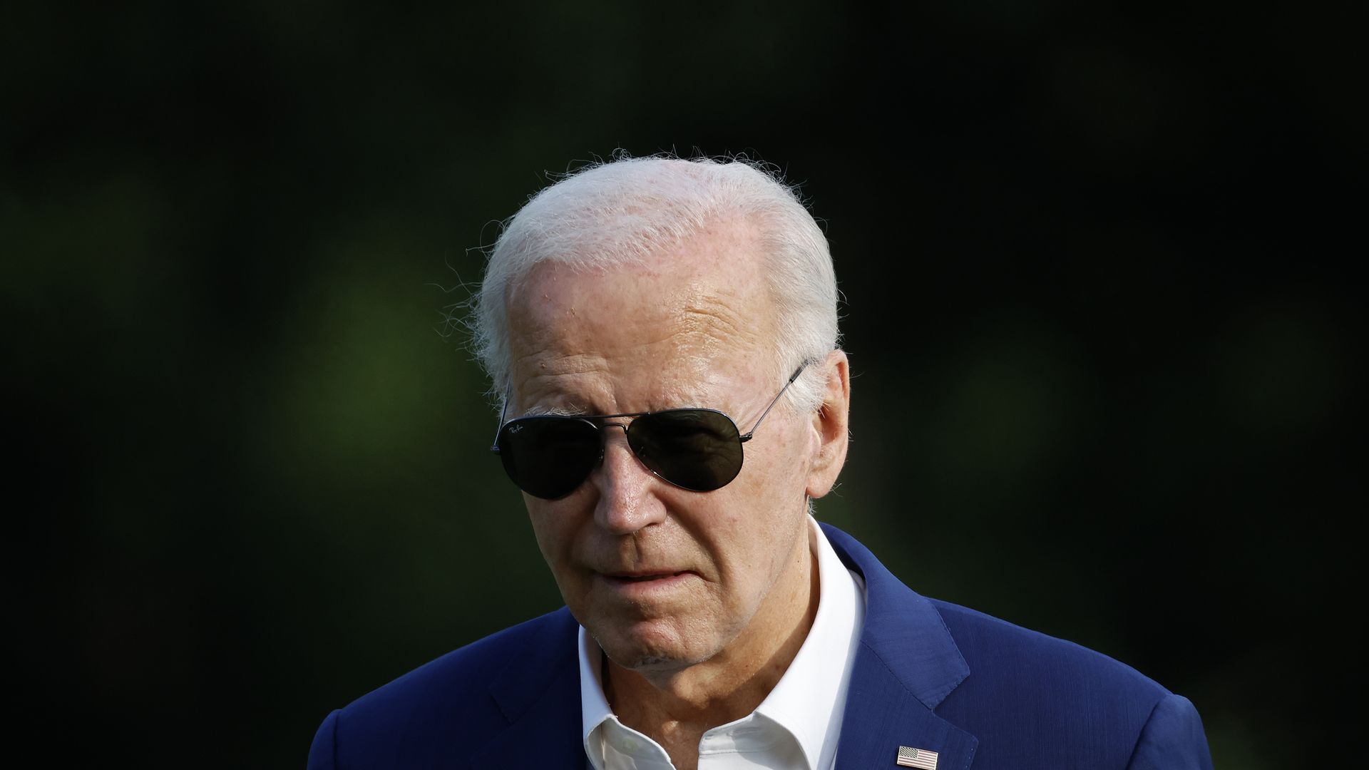 Joe Biden leans forward, wearing sunglasses