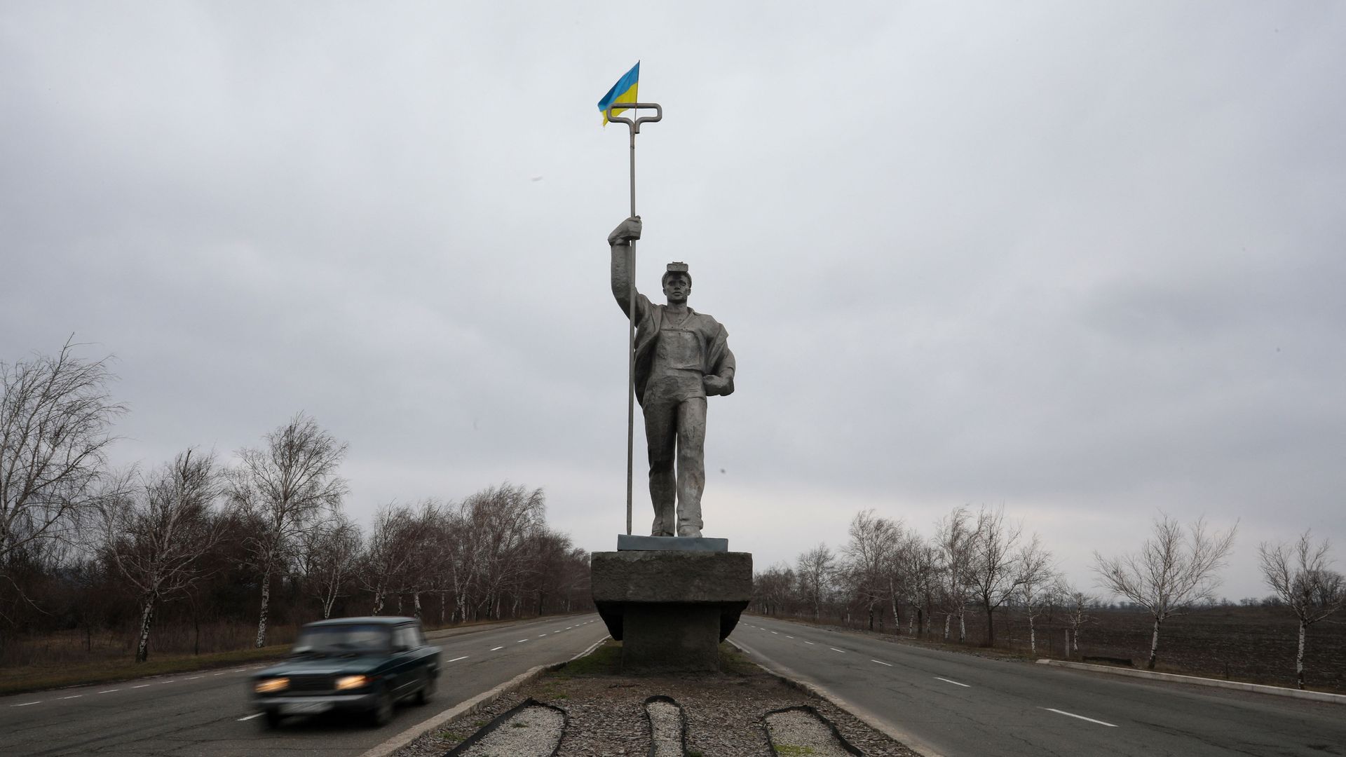 Photo of a statue of a person holding up a Ukrainian flag