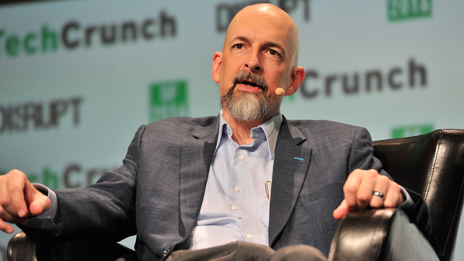 Photo of author Neal Stephenson talking onstage at TechCrunch, wearing a sport jacket